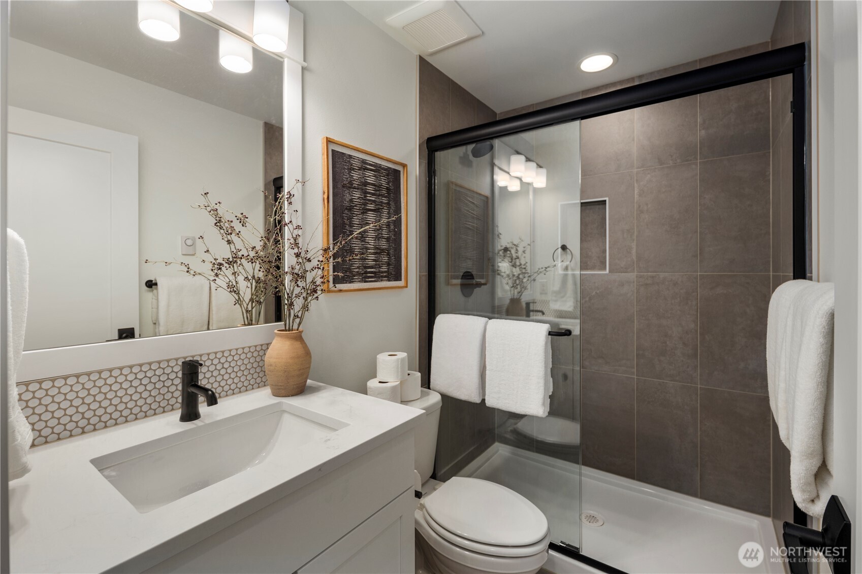 Lower-Level Bathroom: Sleek full bathroom with modern finishes, a frameless glass shower, and designer tile accents. Perfectly situated to serve the lower-level suite or bonus space, it adds functionality and privacy for everyday living or overnight guests.    Photos are from THIS model home at Foxmoore but are for visualization purposes only.