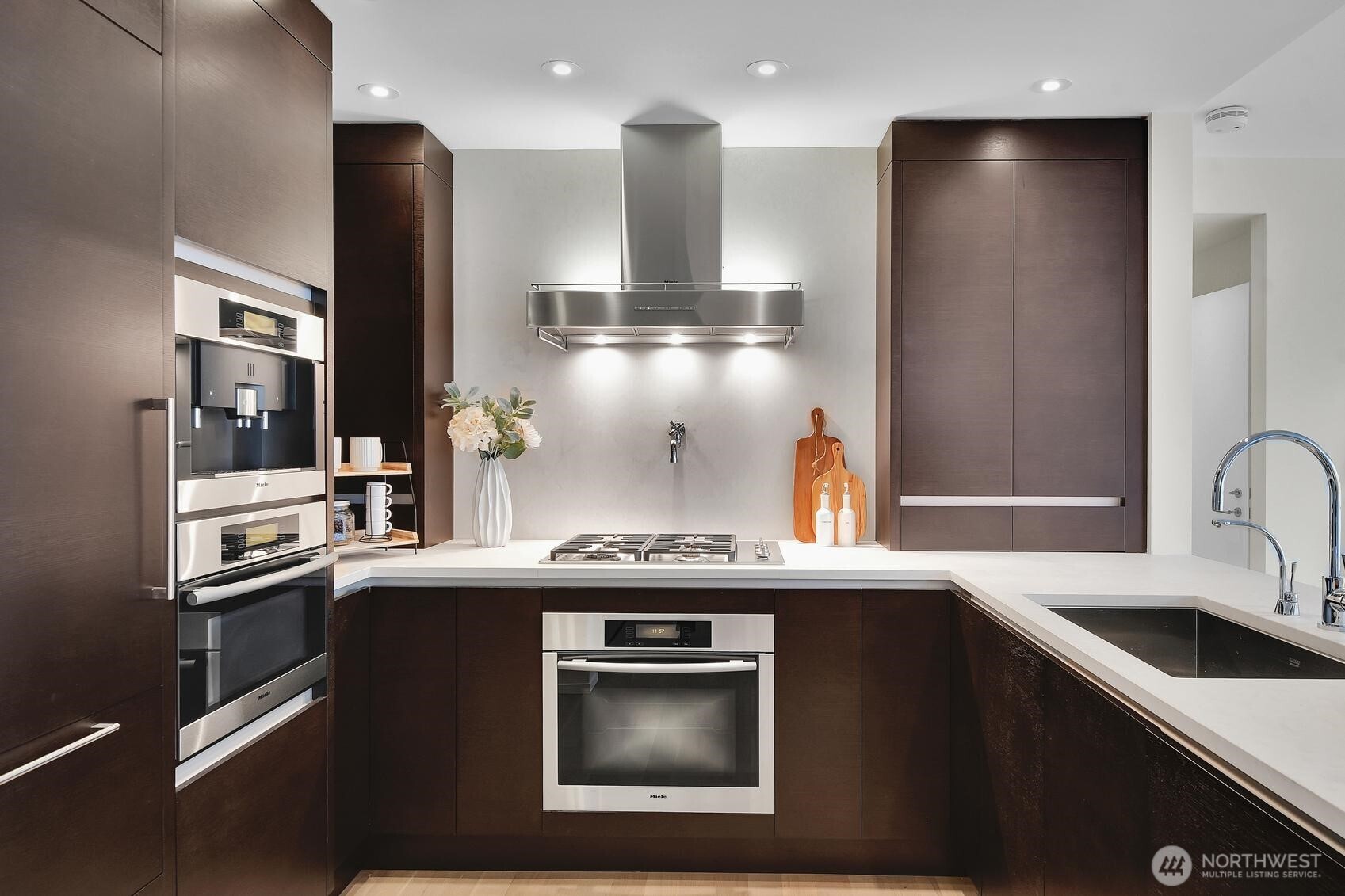 Stone countertops, stainless appliances, and elegant wood cabinetry in the kitchen of Unit 1205