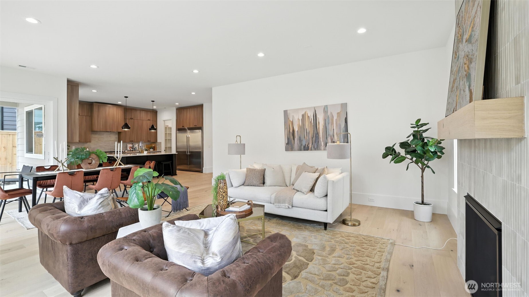 Designed for the way people truly live — connected, open, and beautifully balanced. The kitchen showcases full-height cabinetry, quartz counters, and a striking black island with informal seating. Pendant lighting adds architectural polish, while expansive windows flood the space with natural light. Adjacent, the dining area feels warm and modern, anchored by warm floors and a wall of glass that opens to the backyard — creating seamless indoor-outdoor flow for entertaining and everyday living.