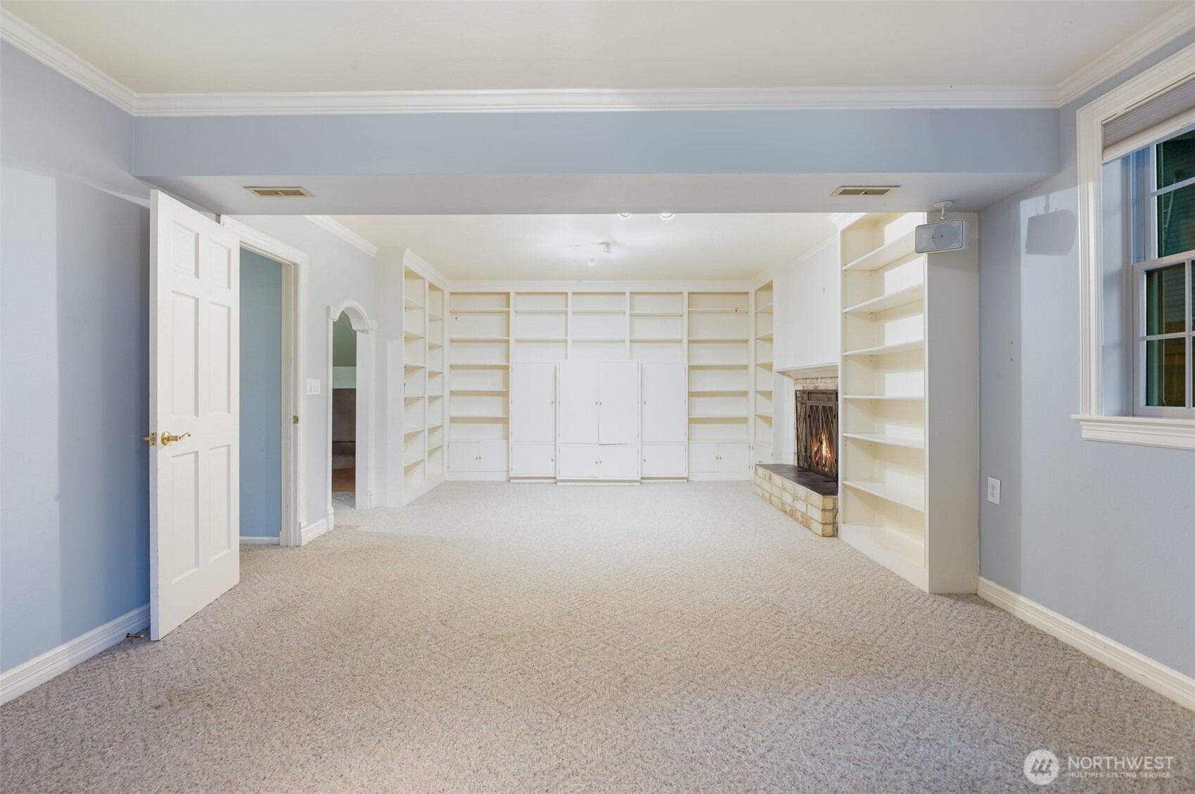 The downstairs bonus room offers a warm and versatile living space, featuring custom built-in shelving, a cozy fireplace, and double interior French doors that add both style and function.