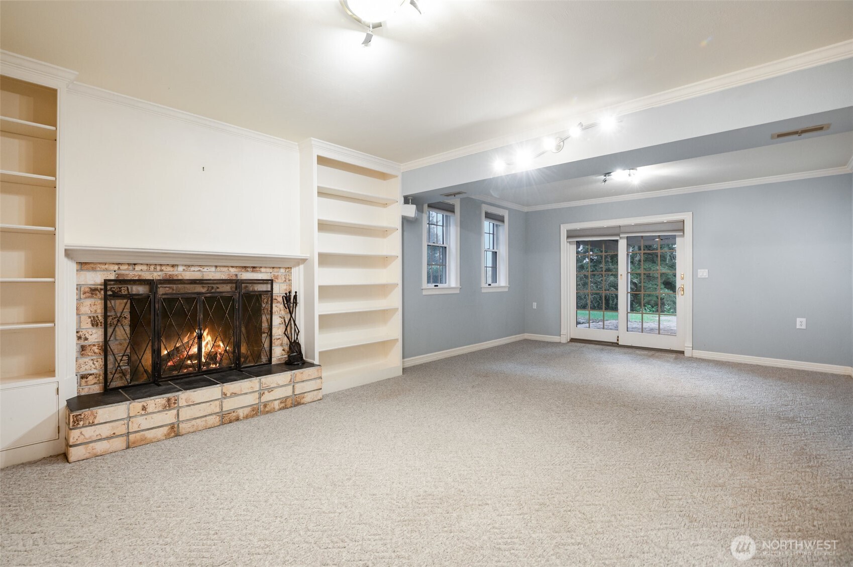 Centered around a charming brick fireplace, the lower-level bonus room includes beautiful custom shelving and elegant French doors, creating the perfect spot for a media room, office, or creative retreat.Centered around a charming brick fireplace, the lower-level bonus room includes beautiful custom shelving and elegant French doors, creating the perfect spot for a media room, office, or creative retreat.