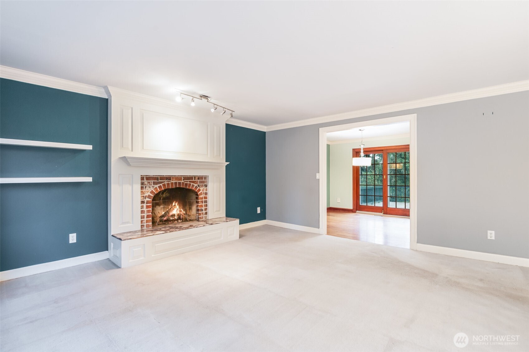 Centered around a modern fireplace and framed by large windows, the living area blends comfort and sophistication with custom floating shelves and a bright, airy ambiance.