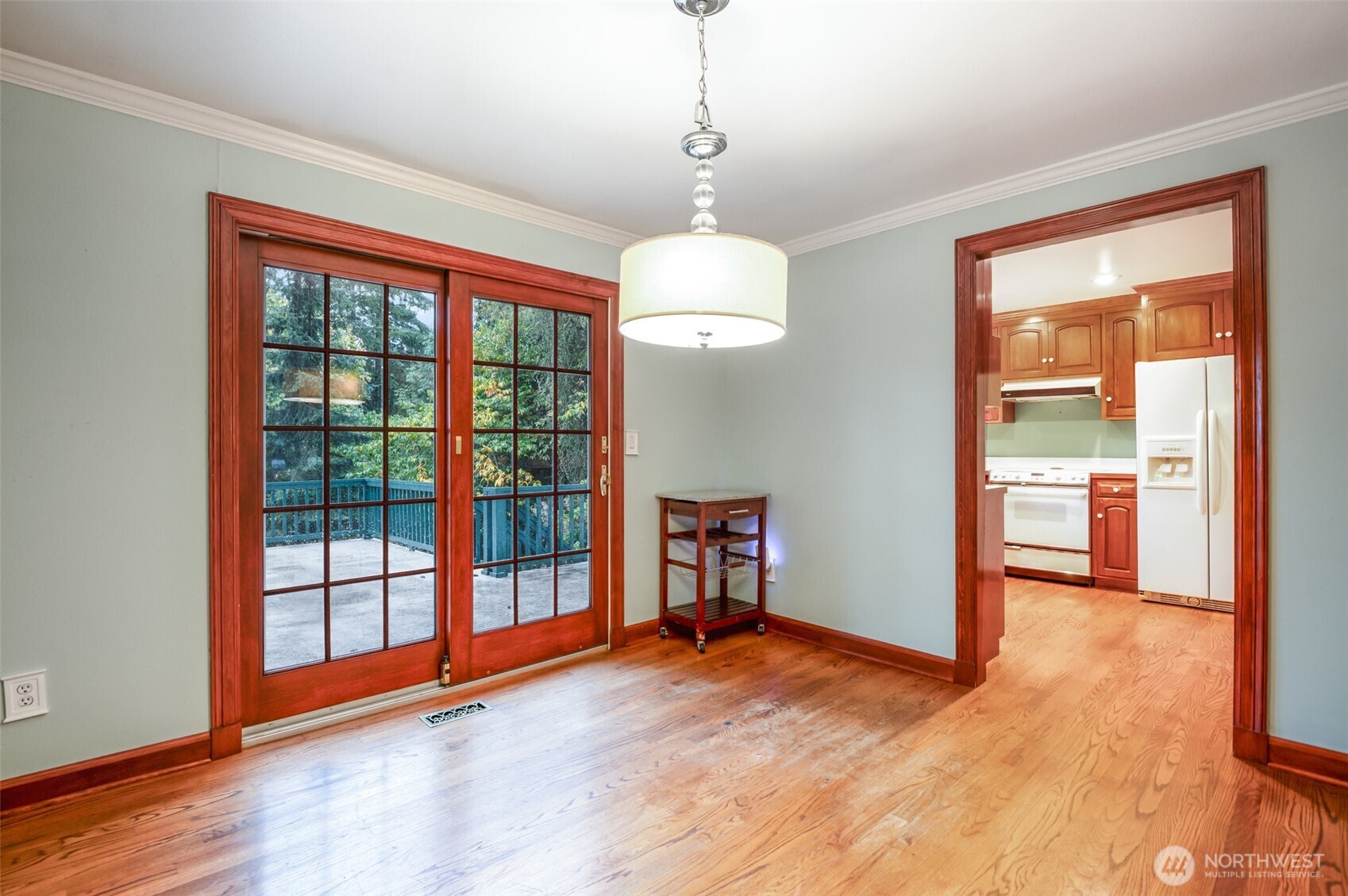 The elegant dining room features rich hardwood floors and double French doors that open to the balcony, inviting in breathtaking views of the mountains and Cottage Lake—an ideal setting for entertaining or quiet evenings at home