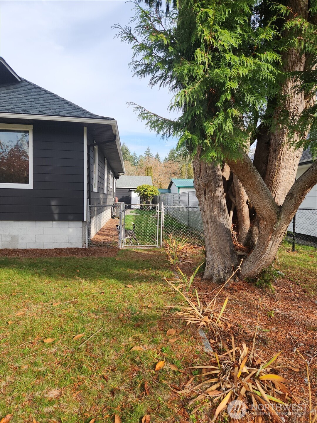 Partial view of the fully fenced backyard and two-car garage in the back ground.