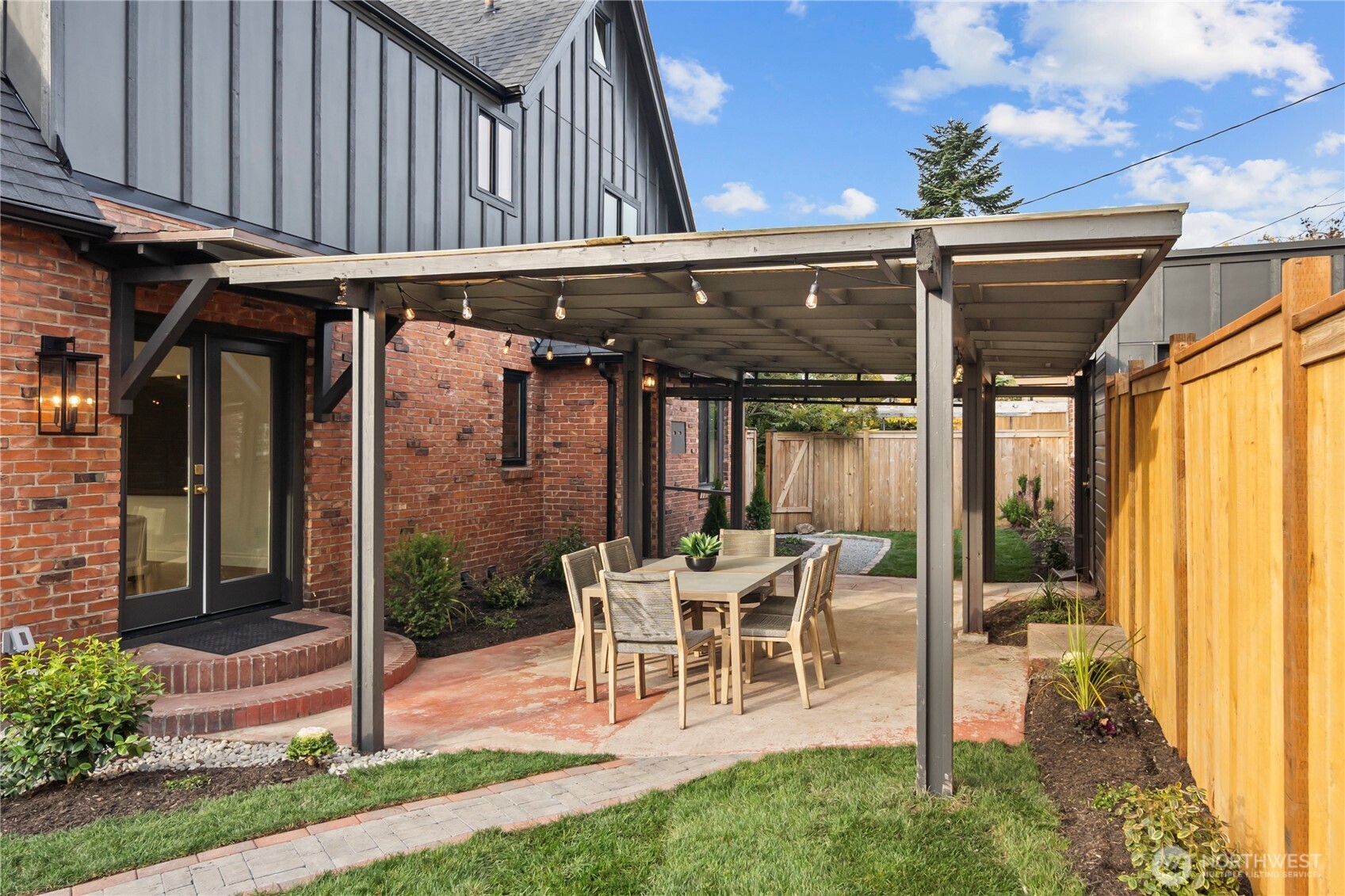 Partial view of the fenced backyard featuring covered walkways from the garage and gate to the home.