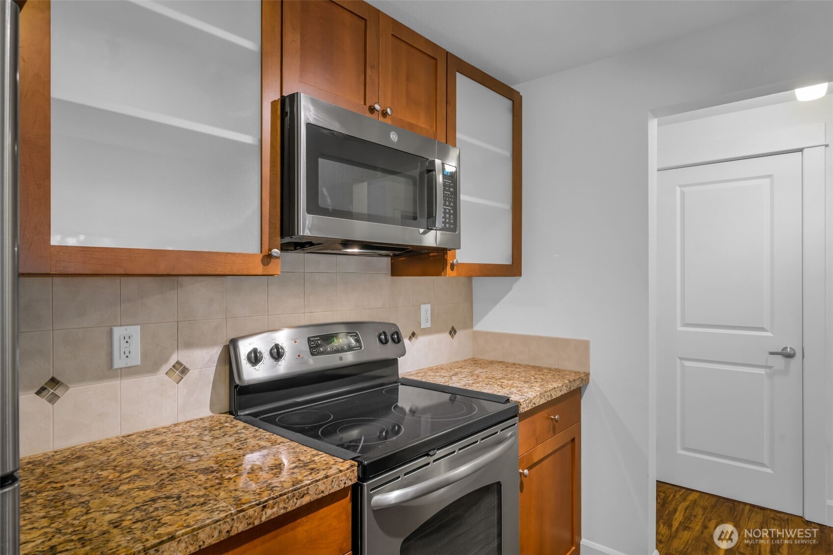 The kitchen has an amazing workspace. Enjoy shaker cabinets, new microwave, glass cooktop and tons of cabinet space. Granite counters and 1 compartment sink.  Tile accents make the space feel modern and clean up is a breeze.