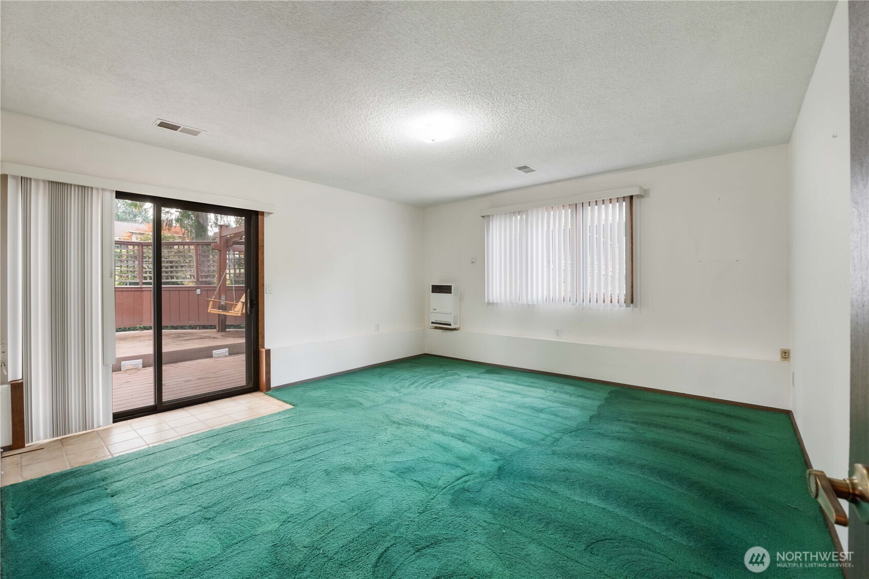 Unstaged Family Room on lower level with slider out to deck and backyard