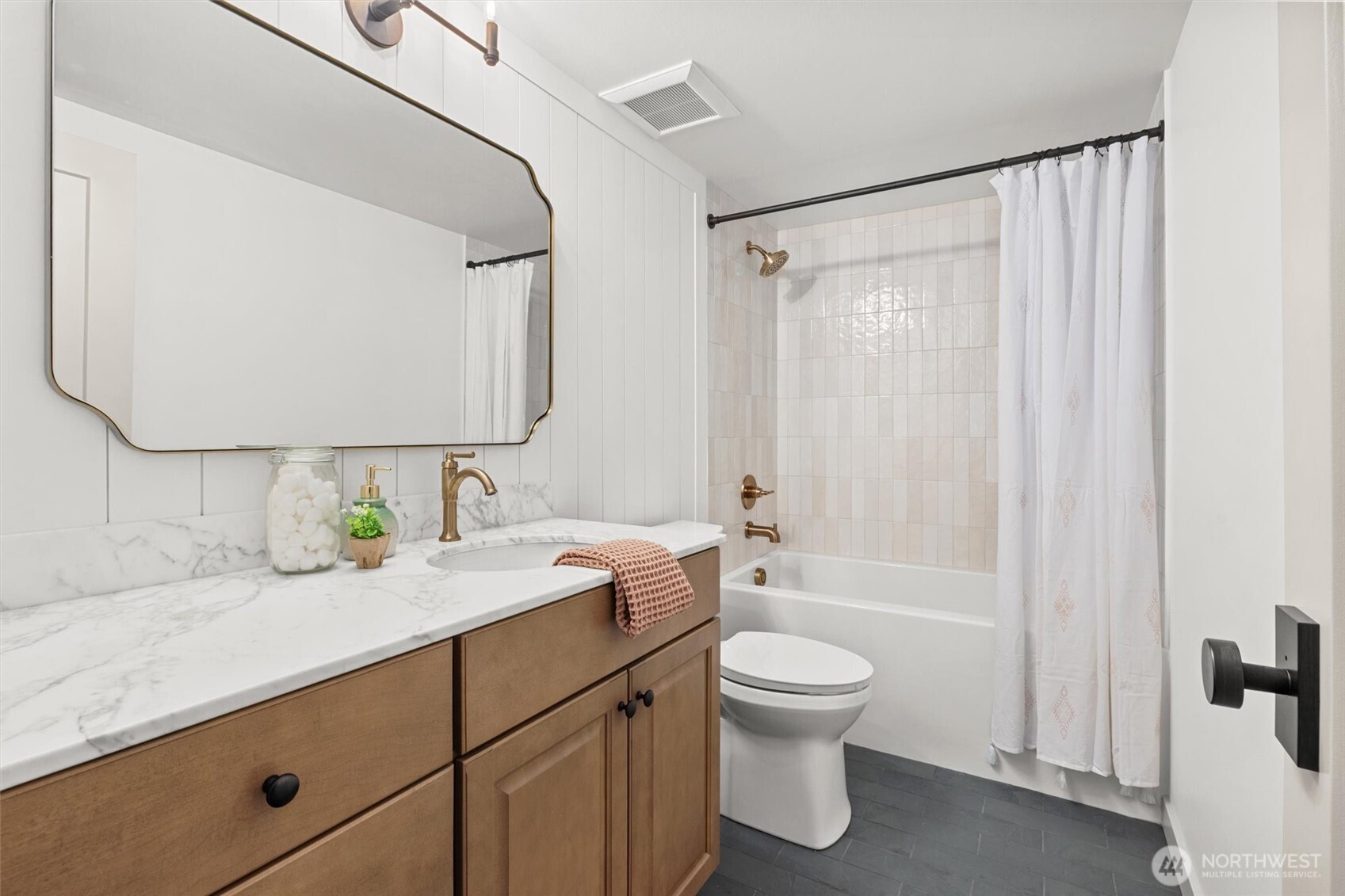 Lower-level full guest bathroom with deep soaking tub, custom tile surround, slate tile flooring, vanity with soft close drawers/doors, marble countertop, shiplap wall detail and high-end plumbing fixtures.