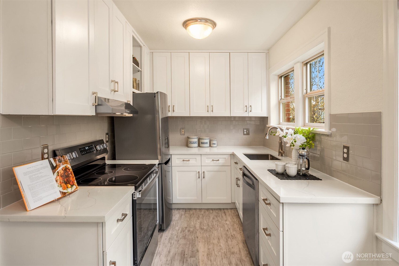Recently updated kitchen that maximizes the space with cabinetry to the ceiling, a new range, quartz countertops, and a pleasant outlook while standing at the sink.