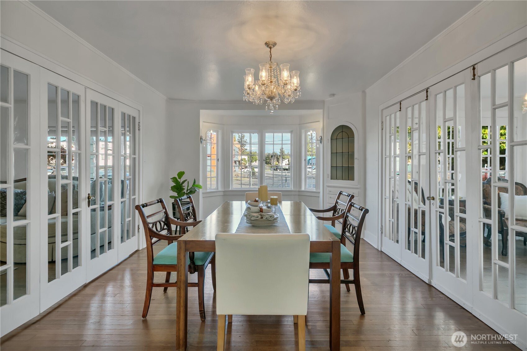 Sun-drenched dining room framed by elegant French folding doors and a classic bay window