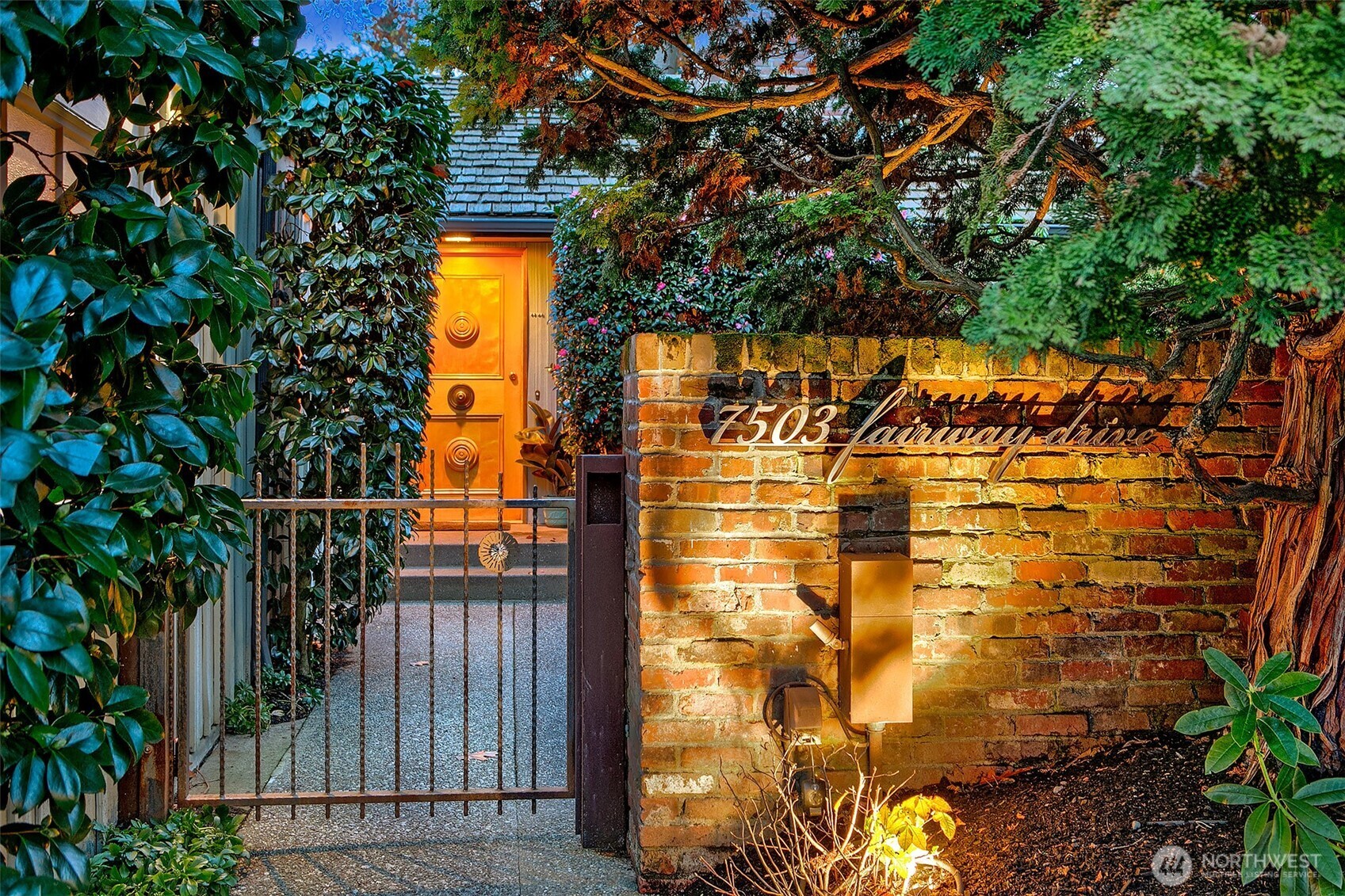 A warm, sheltered entry framed by brick, steel and evergreens sets the tone for life at the Fairway Residence. The custom gate and softly lit courtyard offer a sense of privacy and comfort before opening to the home’s refined interiors.