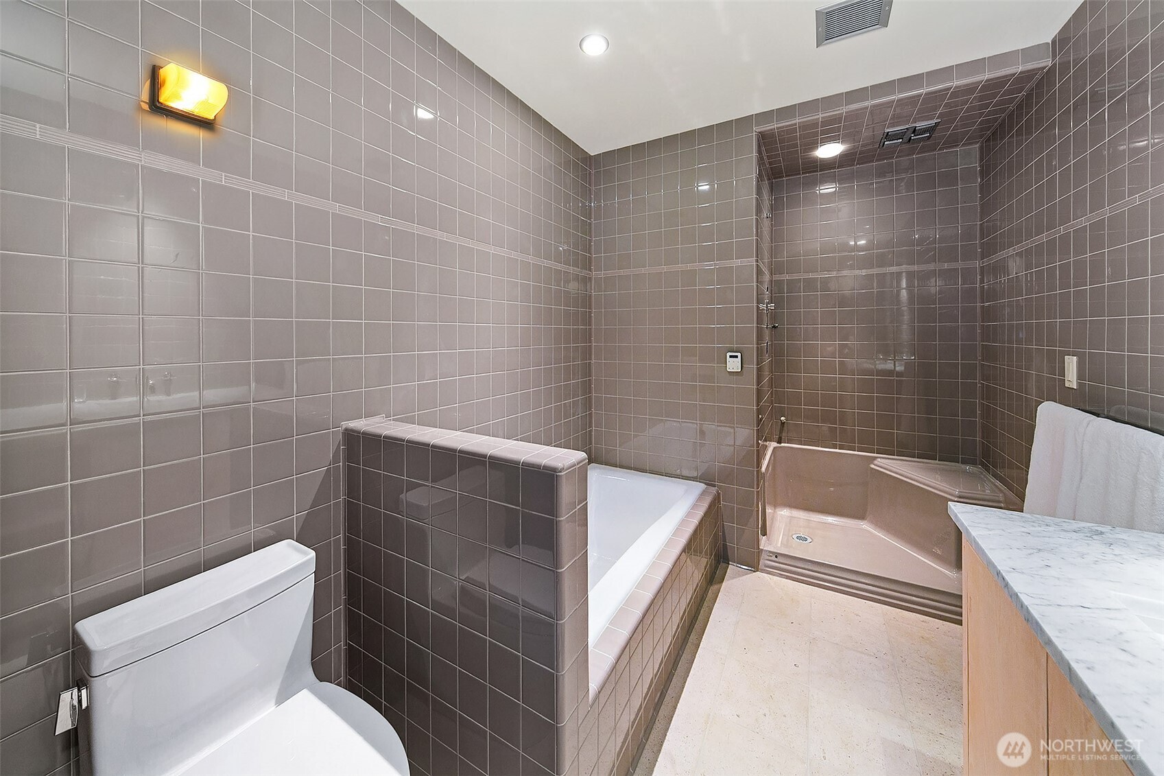 Fully renovated yet faithful to the home’s 1940s aesthetic, this primary bath is wrapped in all-new, custom-selected tile chosen to echo the era’s clean geometry and subtle gloss. The deep soaking tub and oversized walk-in shower sit within a completely rebuilt wet room, featuring modern waterproofing, updated plumbing, and a frameless glass enclosure. A long, stone-slab vanity, radiant-heated floors, and recessed lighting offer contemporary comfort, while the timeless palette and handcrafted detailing preserve the spirit of the original period design.