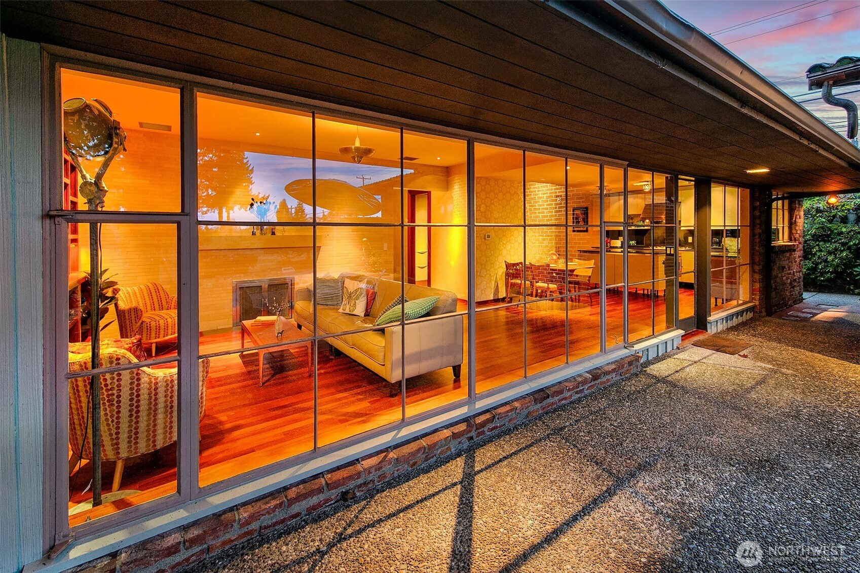 The Great Room is defined by an unusually long wall of floor-to-ceiling commercial steel windows that runs nearly the full width of the home. This dramatic span opens directly to the Lanai and East Terrace and fills the interiors with steady natural light.