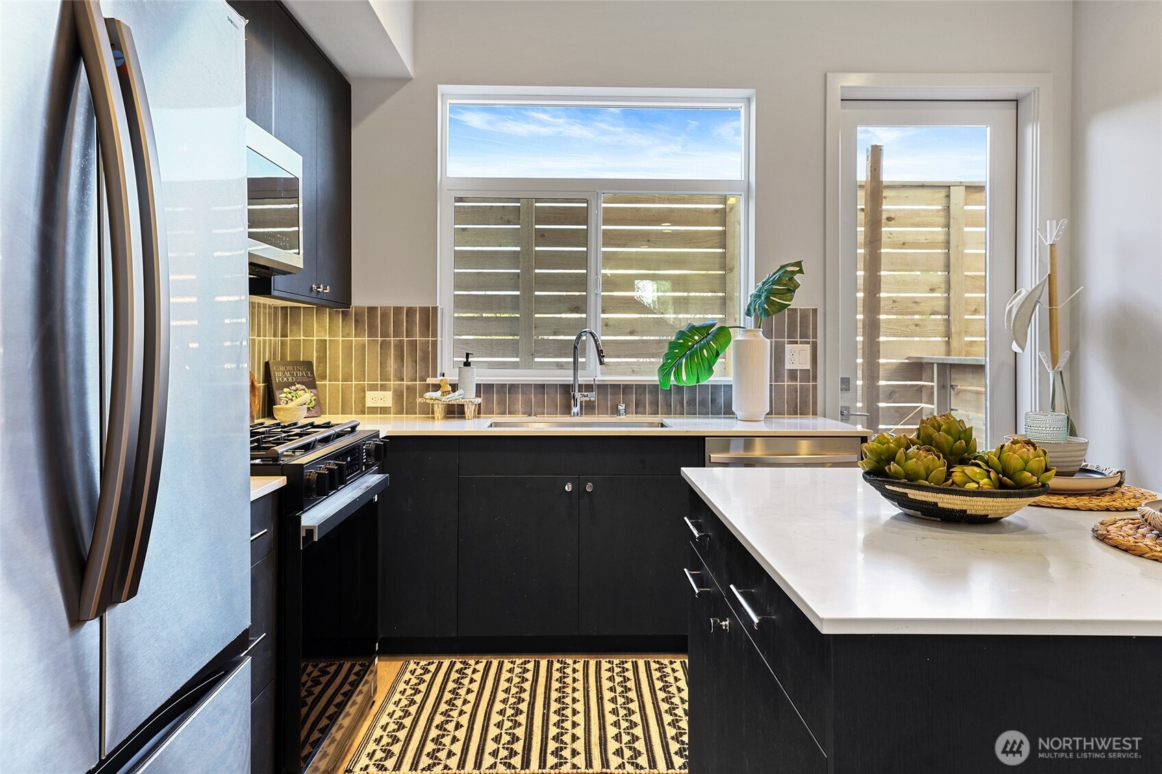 Photos of model home 9752 with similar finishes & floor plan. Bright and stylish, this kitchen combines clean lines with warmth from the natural light and backsplash.