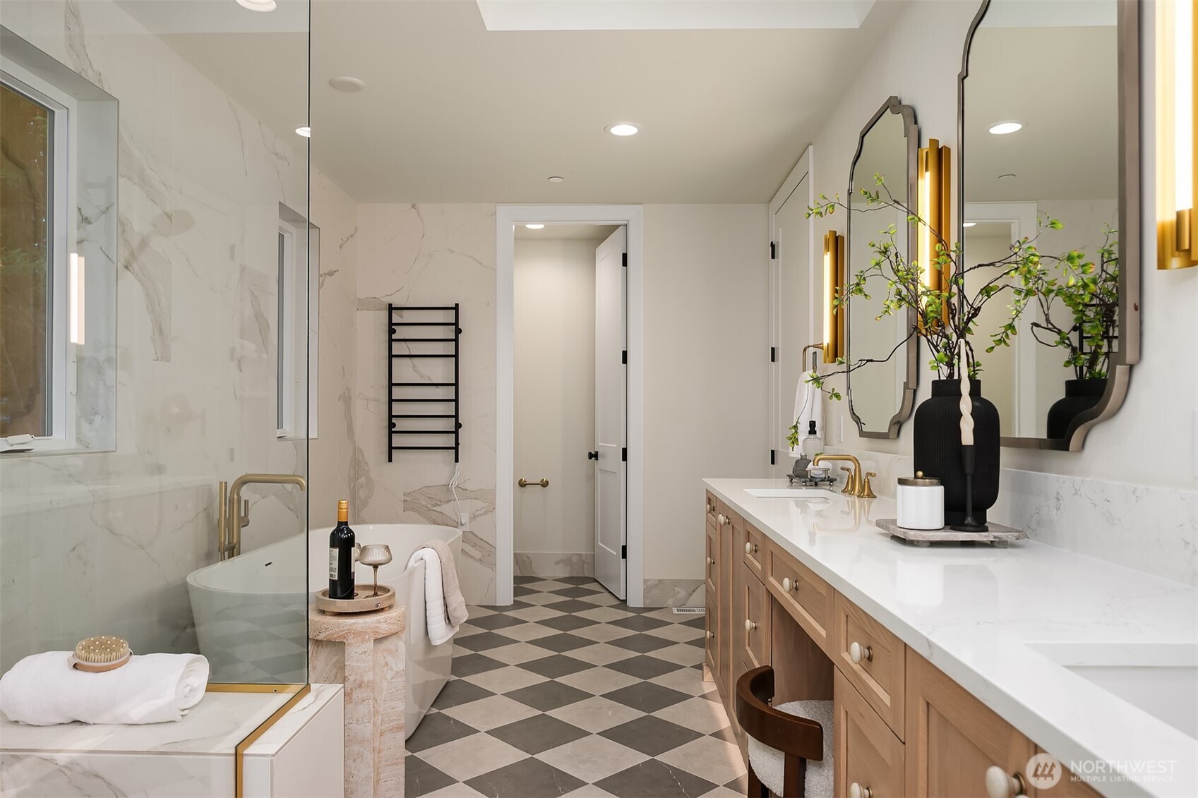 This angle highlights the thoughtful layout of the primary bathroom, featuring radiant heated floors, motion-sensor toe-kick lighting, dual vanity with designer lighting, and a glass-enclosed shower paired with a sculptural soaking tub.