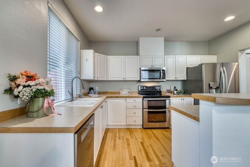 Kitchen showing the stainless steel appliances including dishwasher, garbage disposal, double oven, microwave, and refridgerator with water dispenser/ice maker.