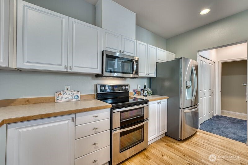 Another view of the kitchen showing the hallway.  Double doors on the left include full size washer and drier.  Coat closet to the right and half bath straight ahead.