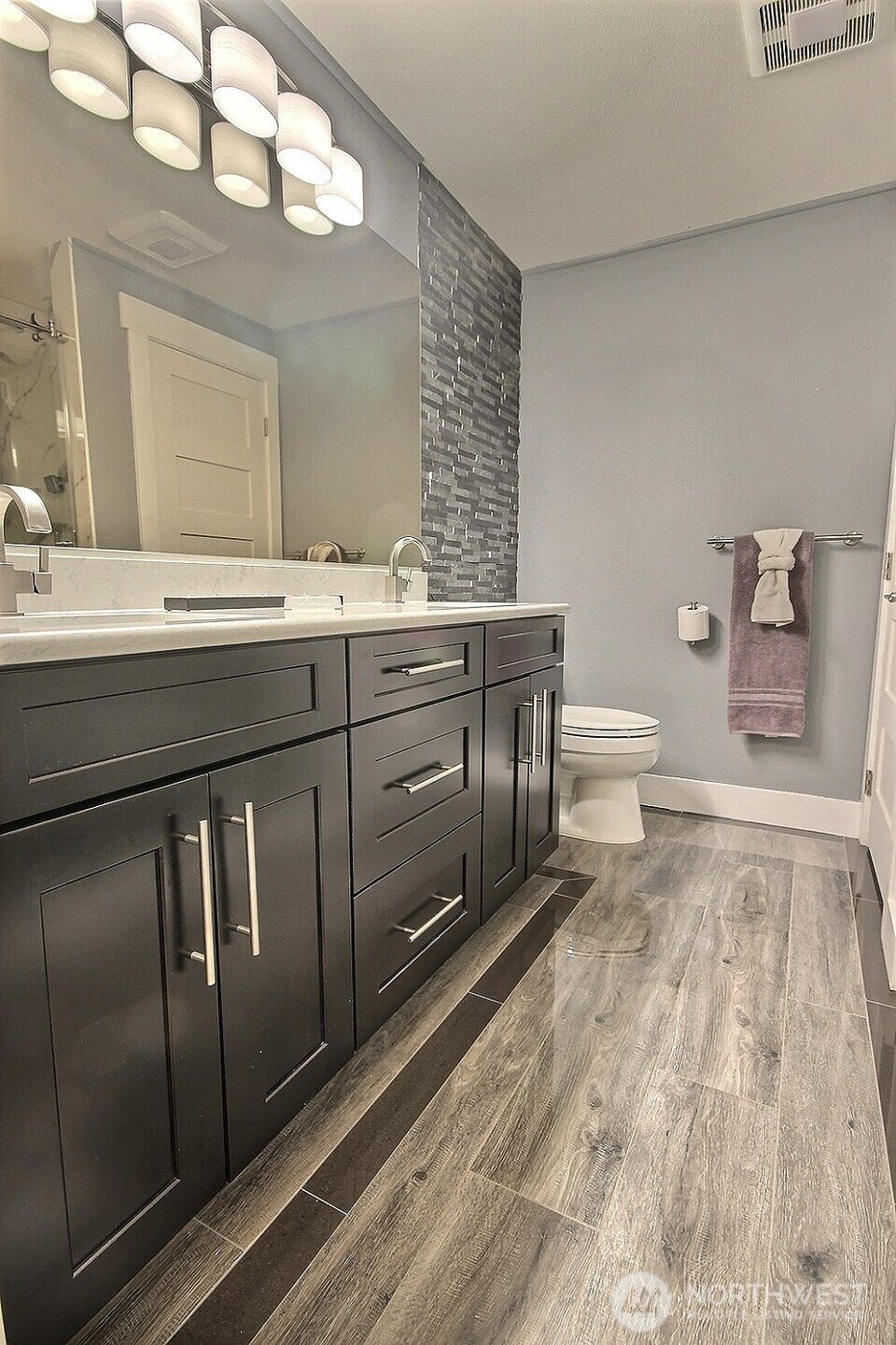 The luxurious spa-like Primary Bathroom with a quartz-top vanity and double sinks boasts heated porcelain floors and a stone-textured wall.