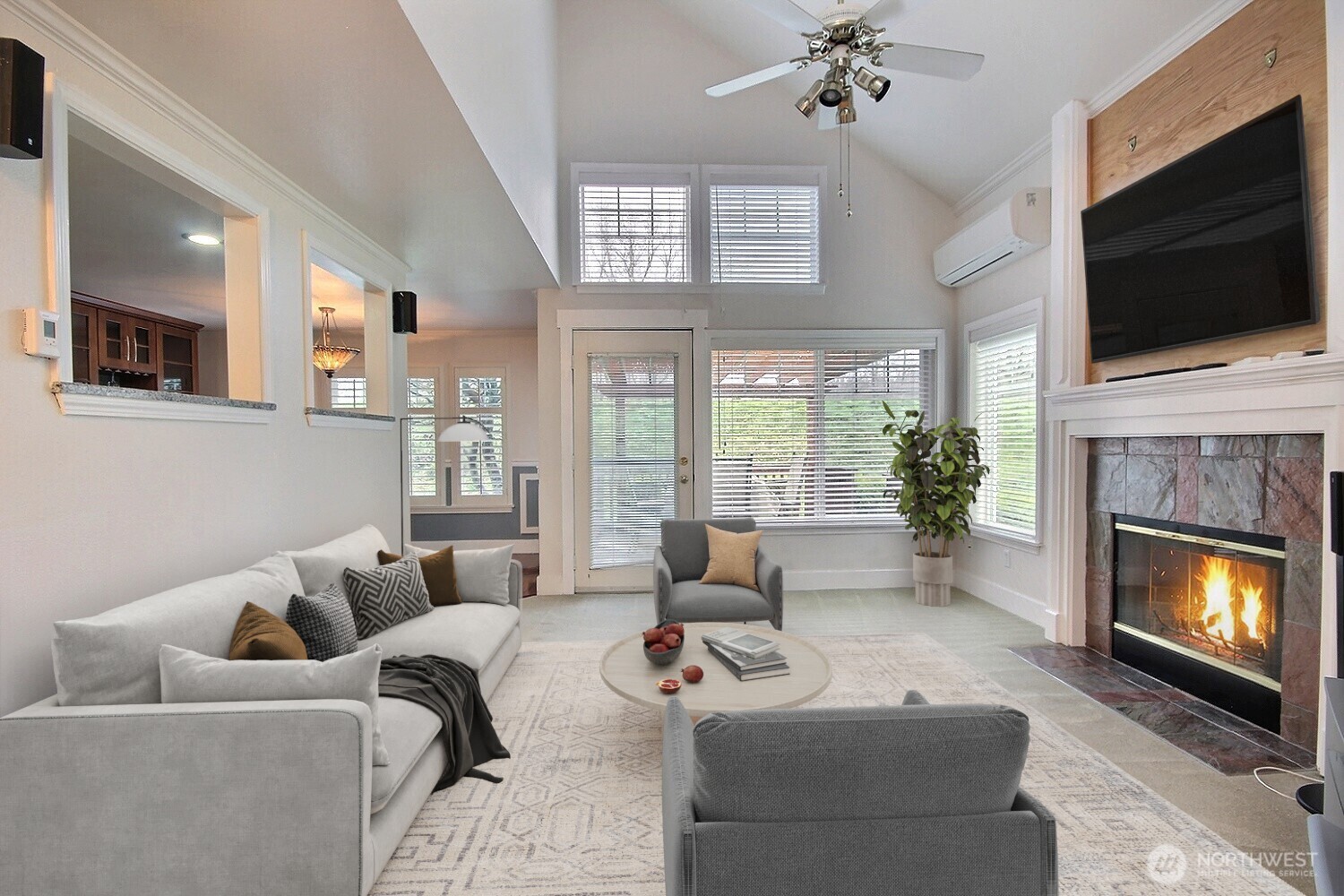 The light-filled living room features vaulted ceilings, a cozy slate-tiled fireplace, and a mini-split air conditioner, creating the perfect space to relax or entertain family and friends. The open layout makes every gathering feel spacious and inviting.