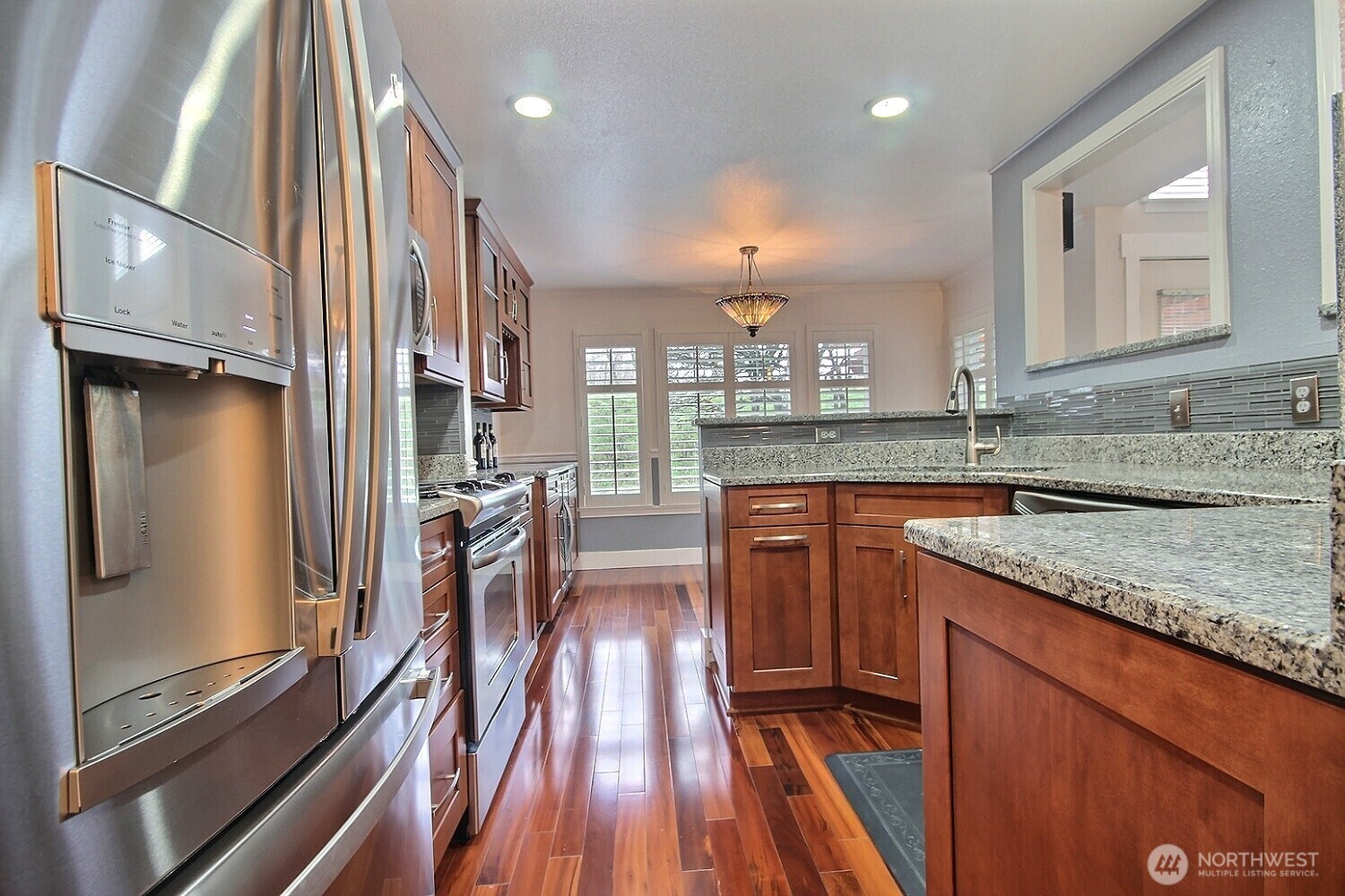 Enjoy cooking in a chef-inspired kitchen featuring hardwood floors, solid wood cabinets, under-counter lighting, stainless steel appliances, and luxurious granite countertops.