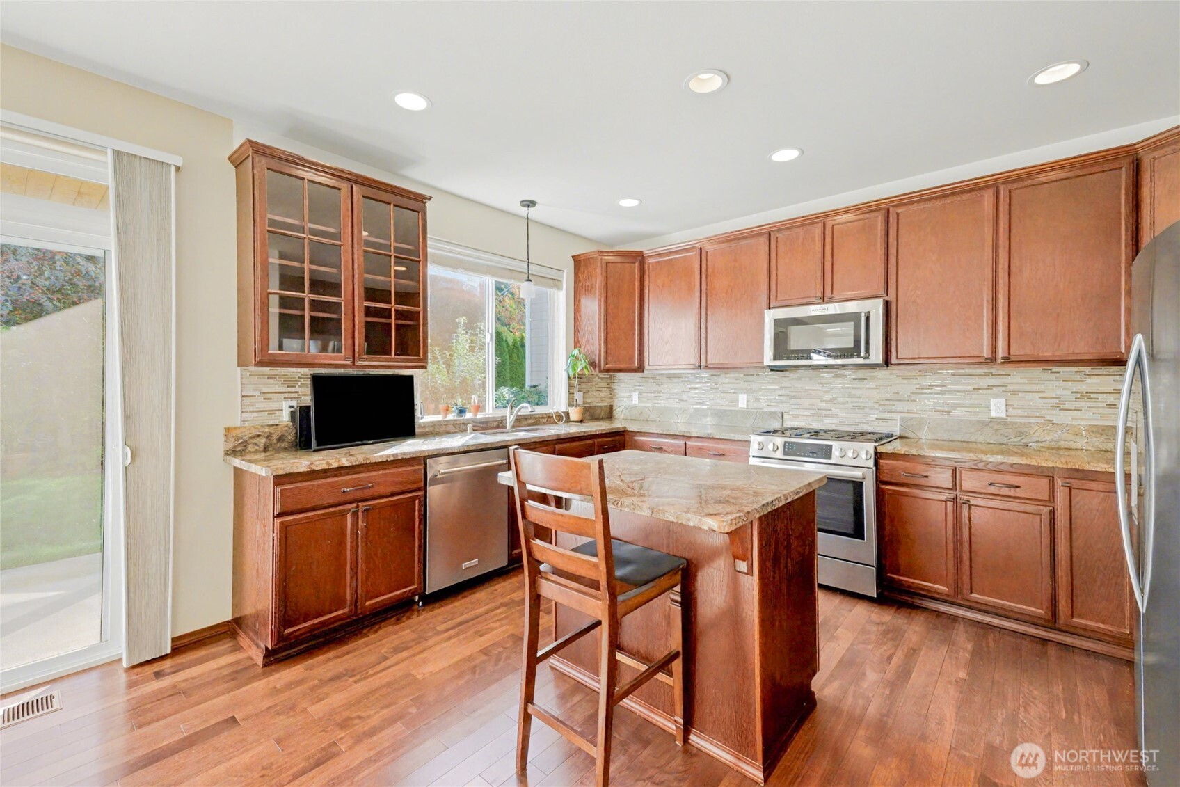The open kitchen is the heart of the home with center island, recessed lighting, and large window above the sink.