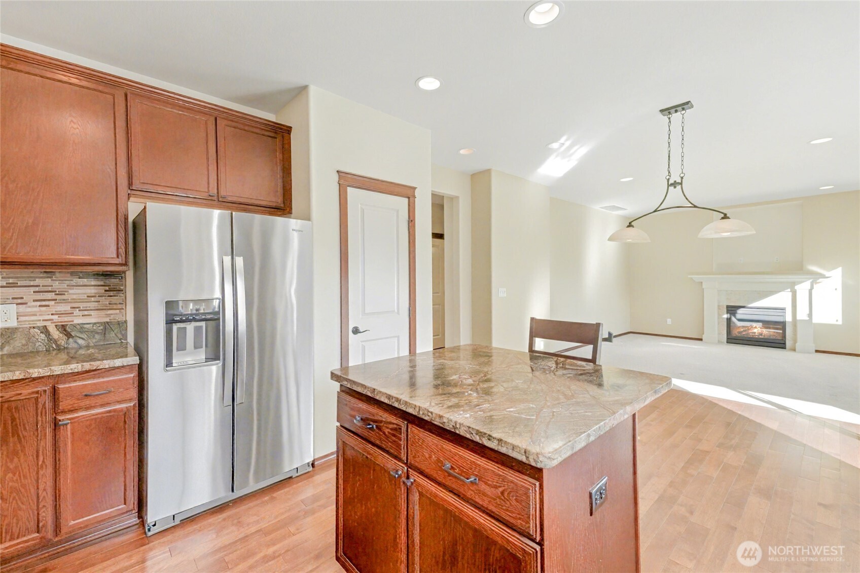 Kitchen boasts warm cabinetry, upgraded stainless steel appliances, hardwood floors & cozy island with seating for 2.