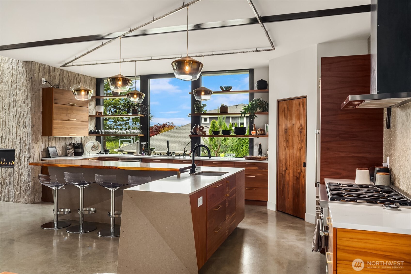 Rich walnut cabinets and custom quartz island with bar top seating. Corner walk-in pantry storage