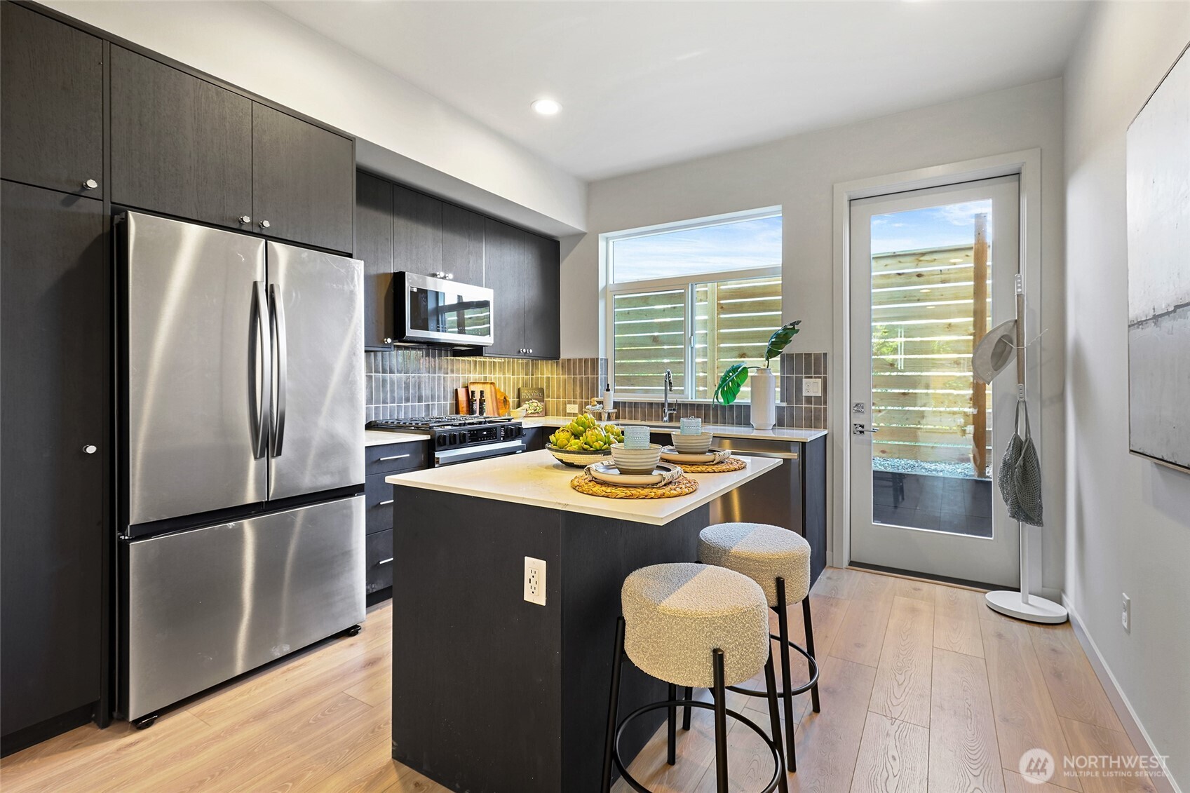Photos of model home 9752 with similar finishes & floor plan. The chef-inspired kitchen features a large island with seating, stainless steel appliances, and designer cabinetry.