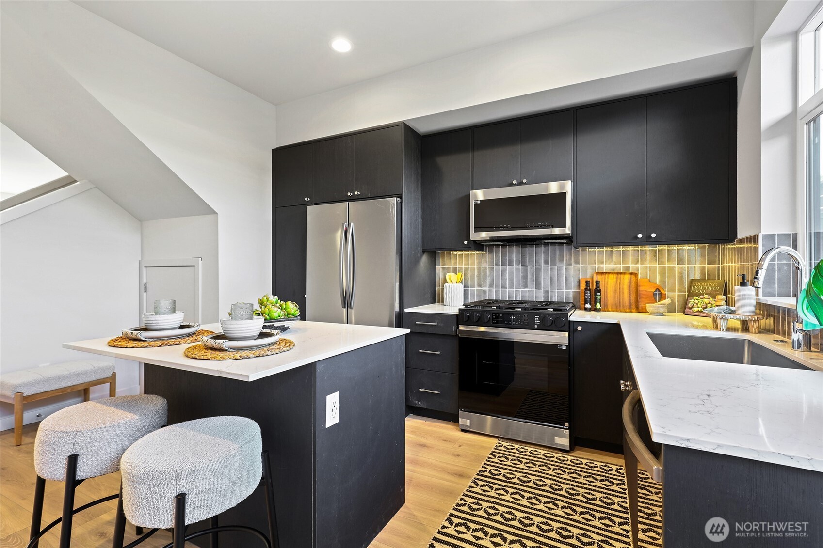 Photos of model home 9752 with similar finishes & floor plan. Ready to impress — this modern kitchen features a large peninsula with bar seating, gleaming quartz counters, and full-size stainless steel appliances that elevate everyday living.