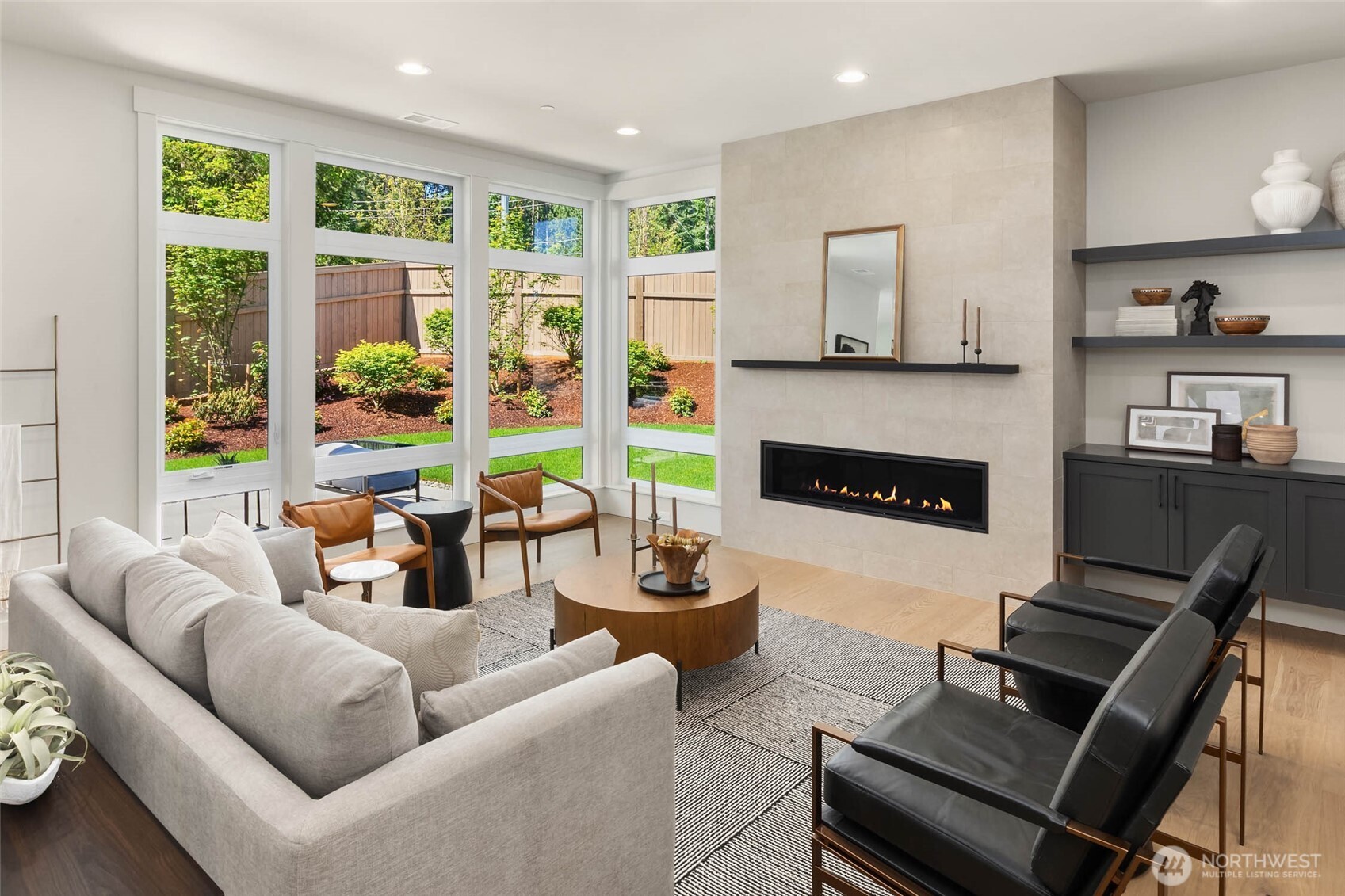 Great room living space flanked by full height tile feature wall with contemporary linear fireplace