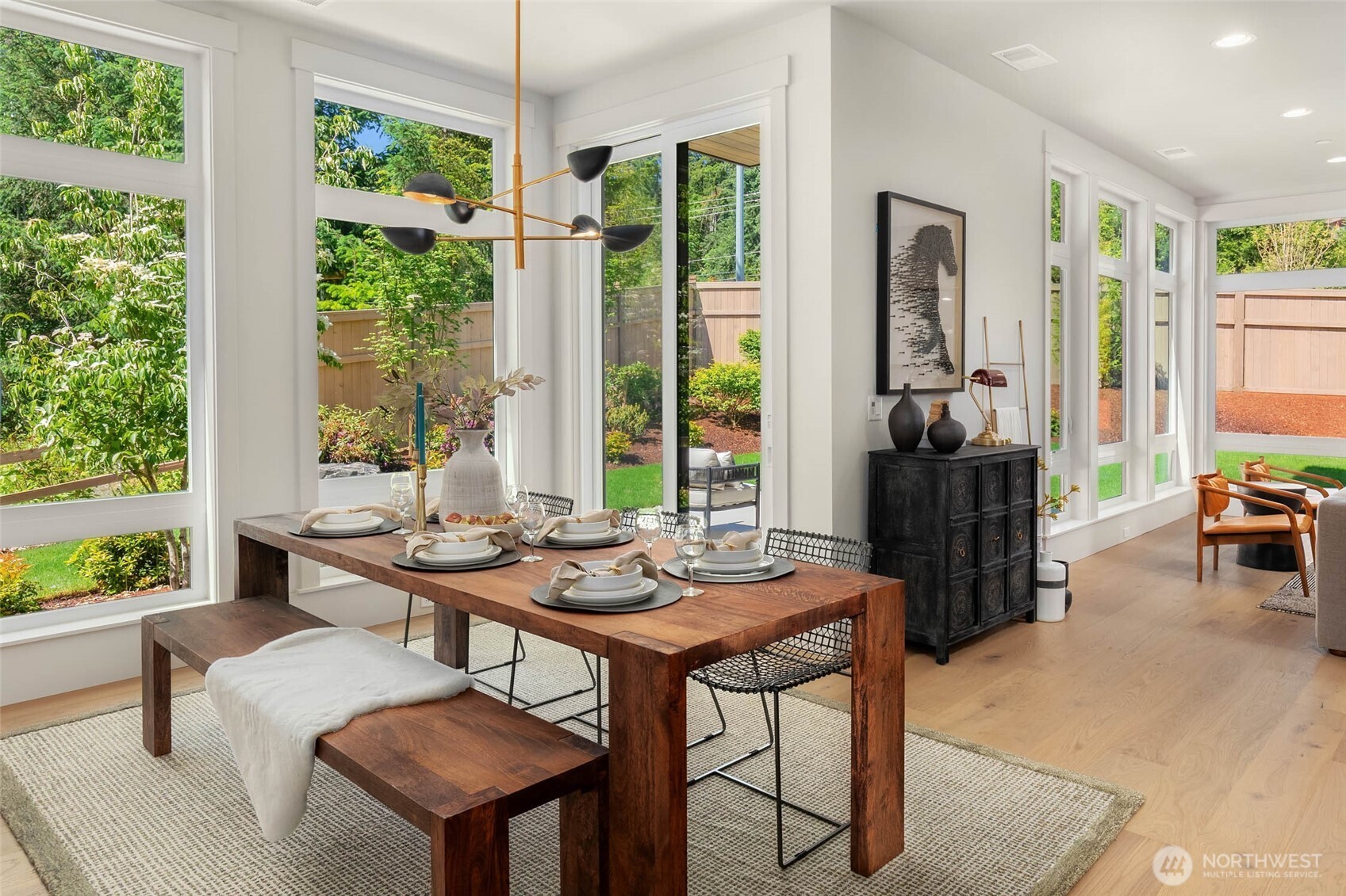 Dedicated dining space off kitchen and living area with designer selected hanging fixture is surrounded by window walls and opens to back yard entertaining spaces