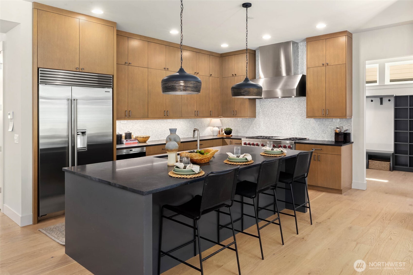 Chefs kitchen includes custom built cabinets to the ceiling with tile backsplash and built in refrigerator