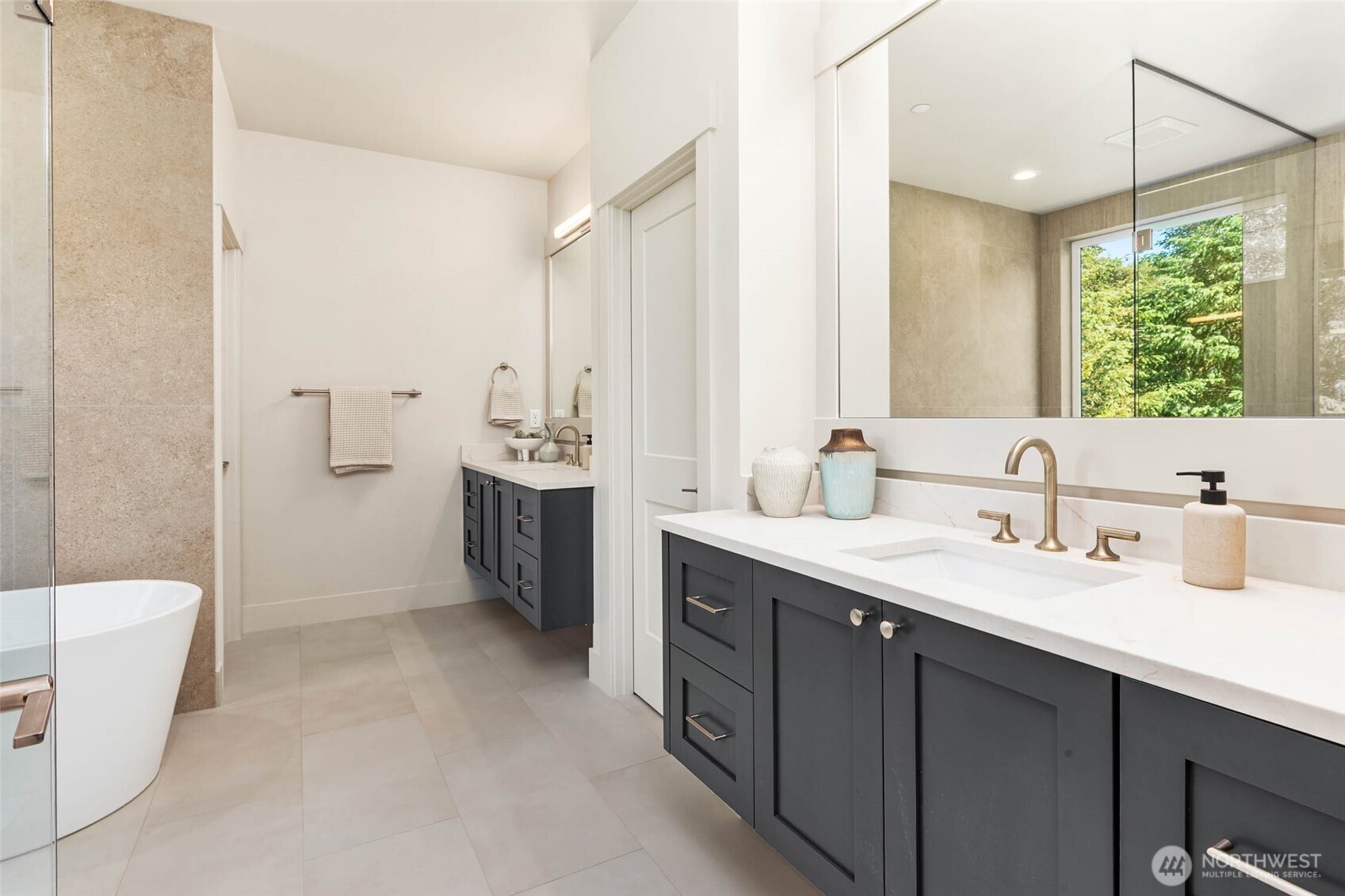 Primary bath features double custom built floating cabinets with slab counters and undermount sinks