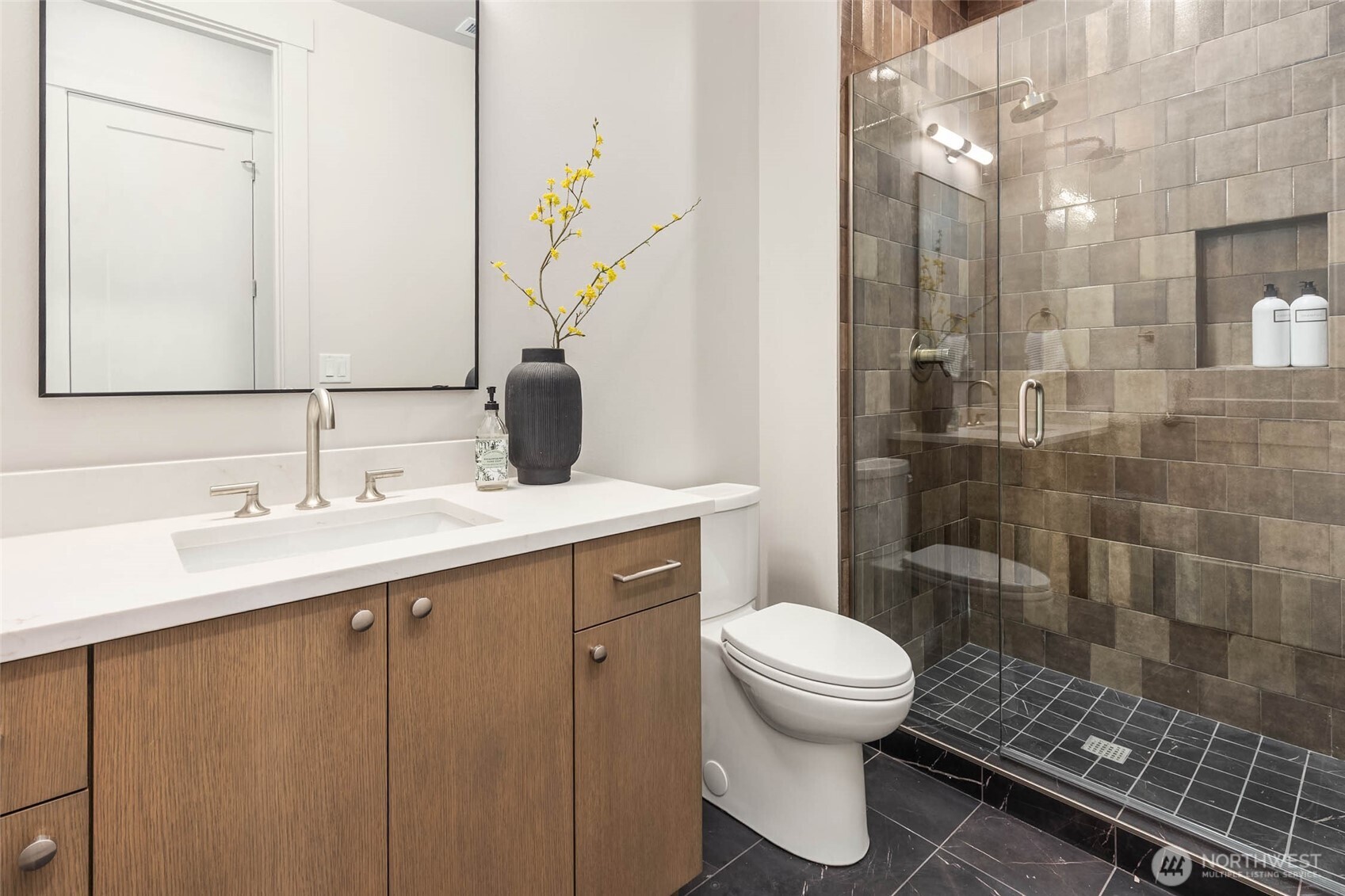 Main Floor 3/4 bath adjacent to office/5th bedroom with custom cabinets and slab counter, and mud set tile shower with frameless glass enclosure