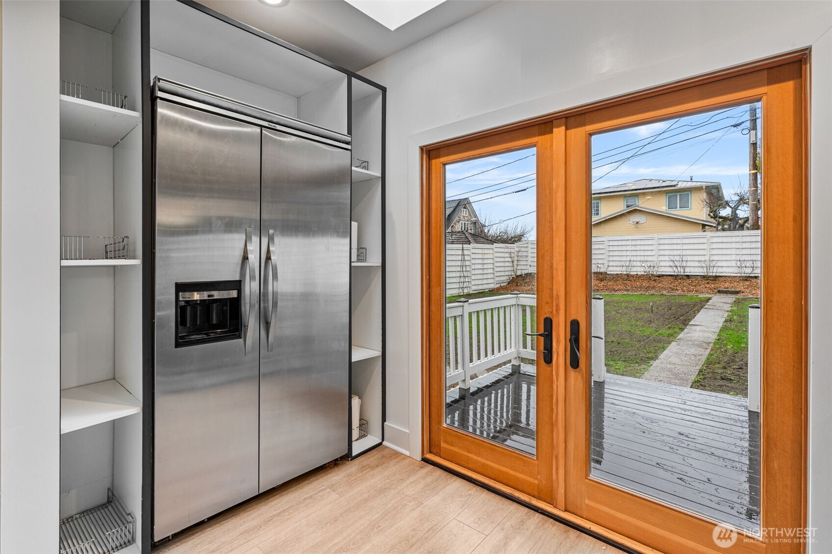 Viking stainless steel refrigerator and new Pella French doors open to new deck space and fully fenced level backyard