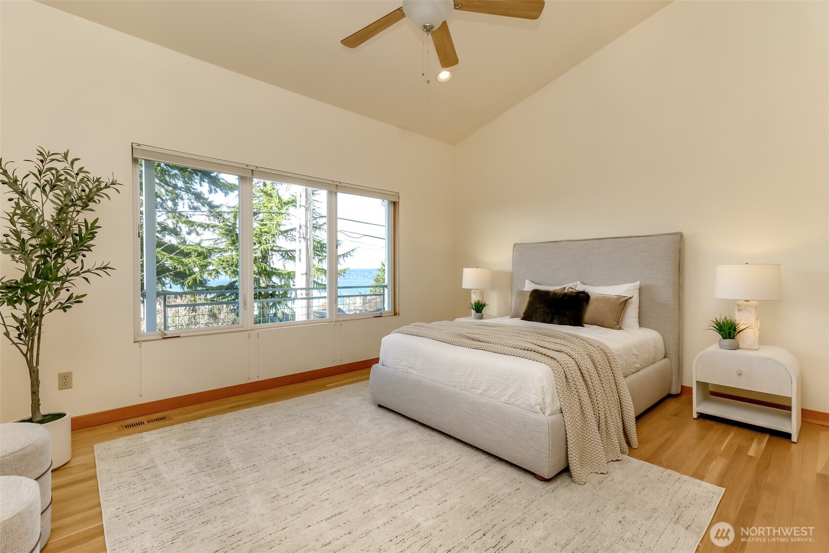 Large master bedroom with large view windows and ceiling fan