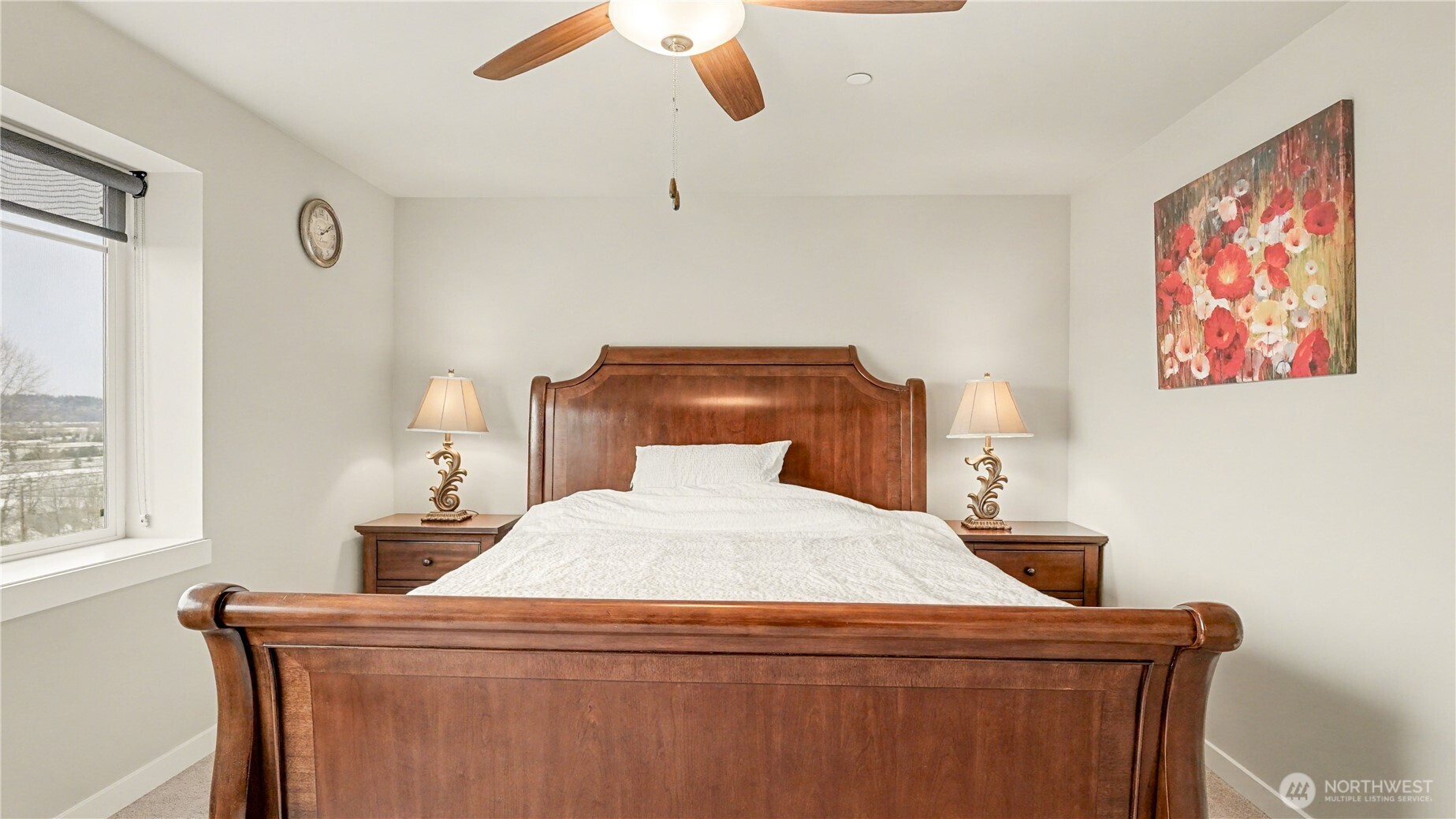 Primary suite features a ceiling fan and a large window that fills the room with natural light