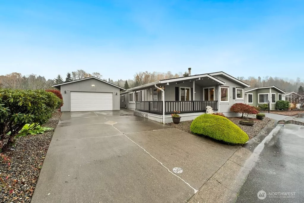 Explore this inviting corner lot featuring a well-maintained driveway leading to a spacious separate two-car garage equipped with valuable shop space at the back, ideal for hobbies or projects. The property also includes a handy storage shed for additional organization. The charming front porch of the house adds to the curb appeal, perfect for enjoying peaceful moments in this serene 55-plus gated community.