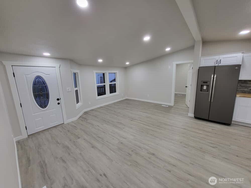 Heading toward the doorway next to the fridge, into room #1 (that has full bath directly off)