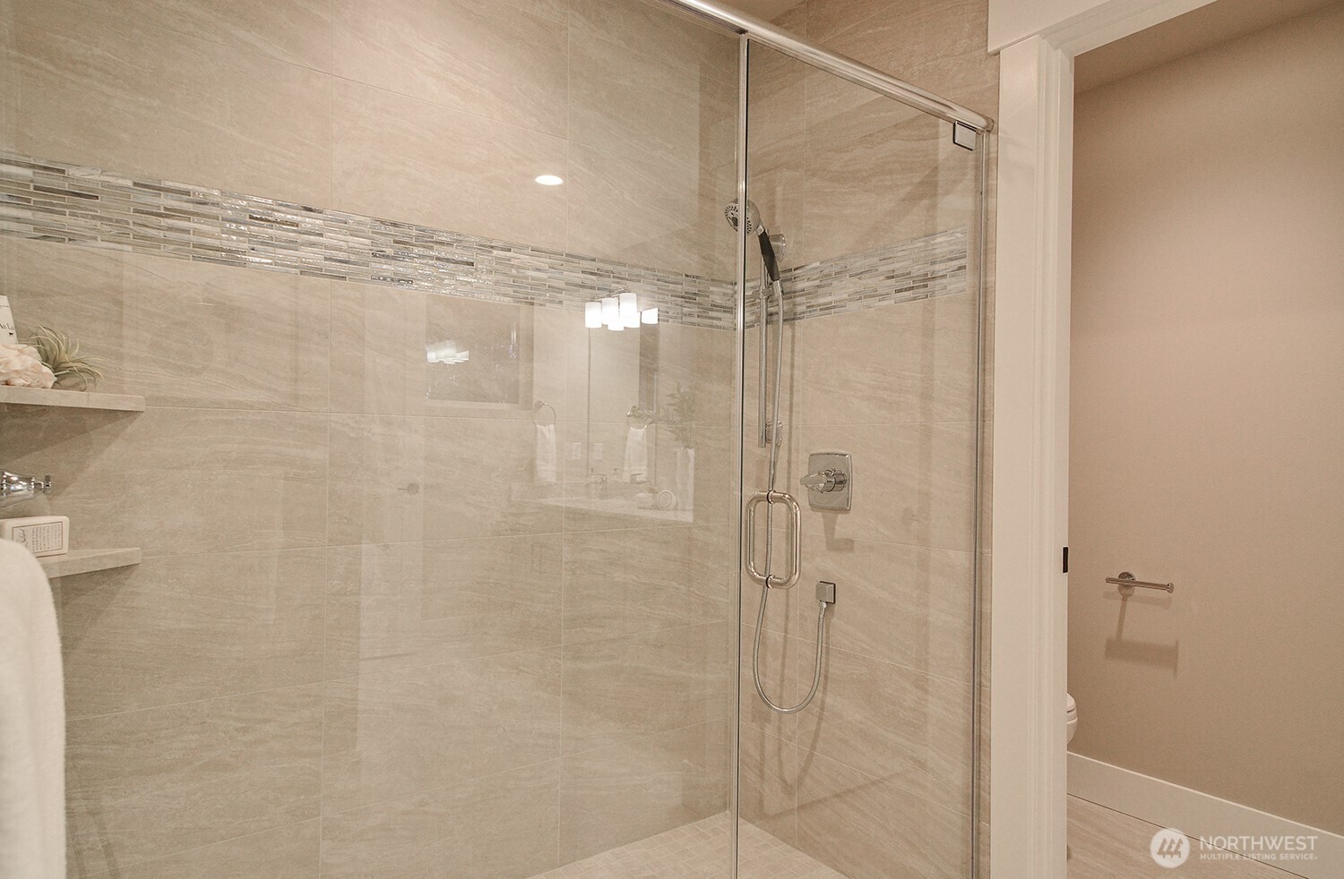Large tiled shower with glass door in the primary bath.