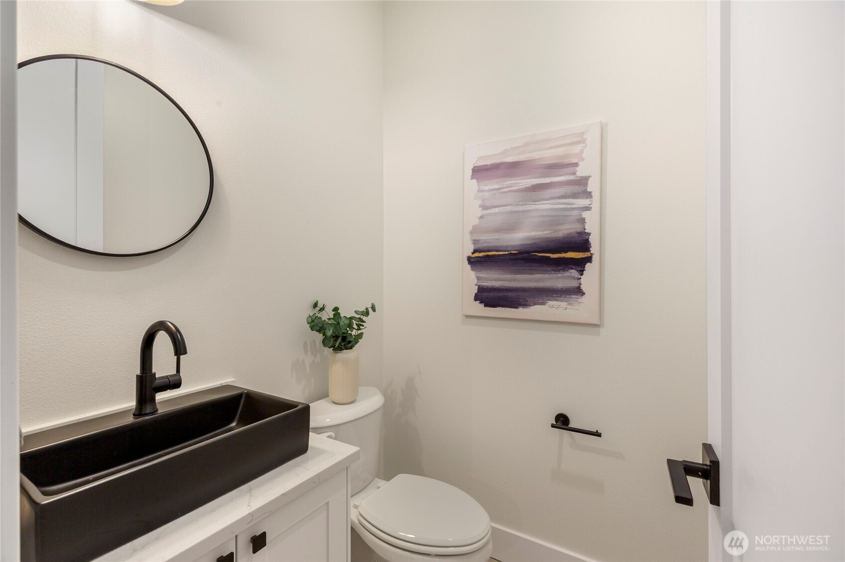 Bathroom with quartz countertop, recessed lighting, white walls, and black fixtures.