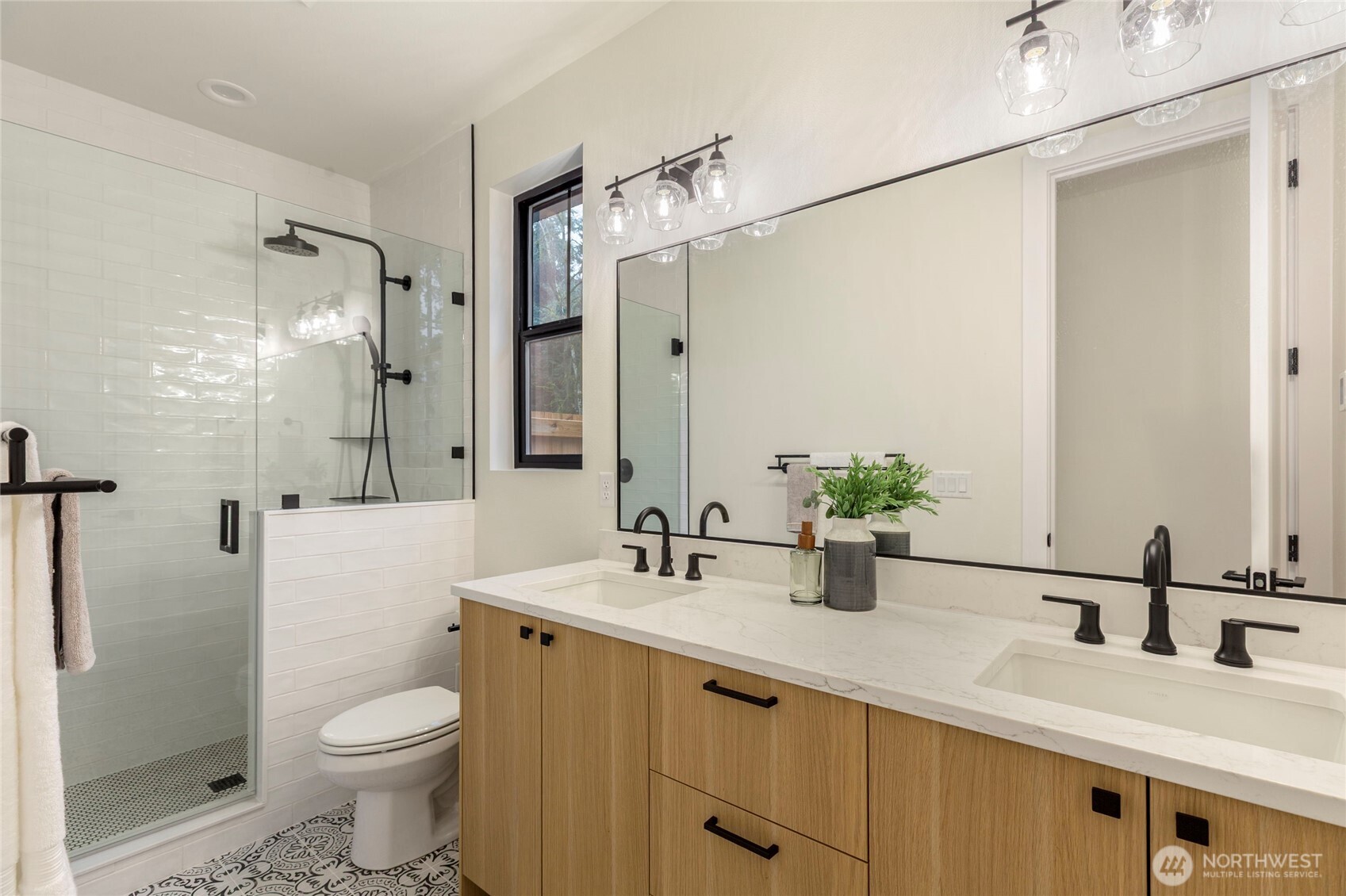 Full bath connected to first floor primary bedroom, glass-enclosed shower with marble accents, and a quartz countertop.