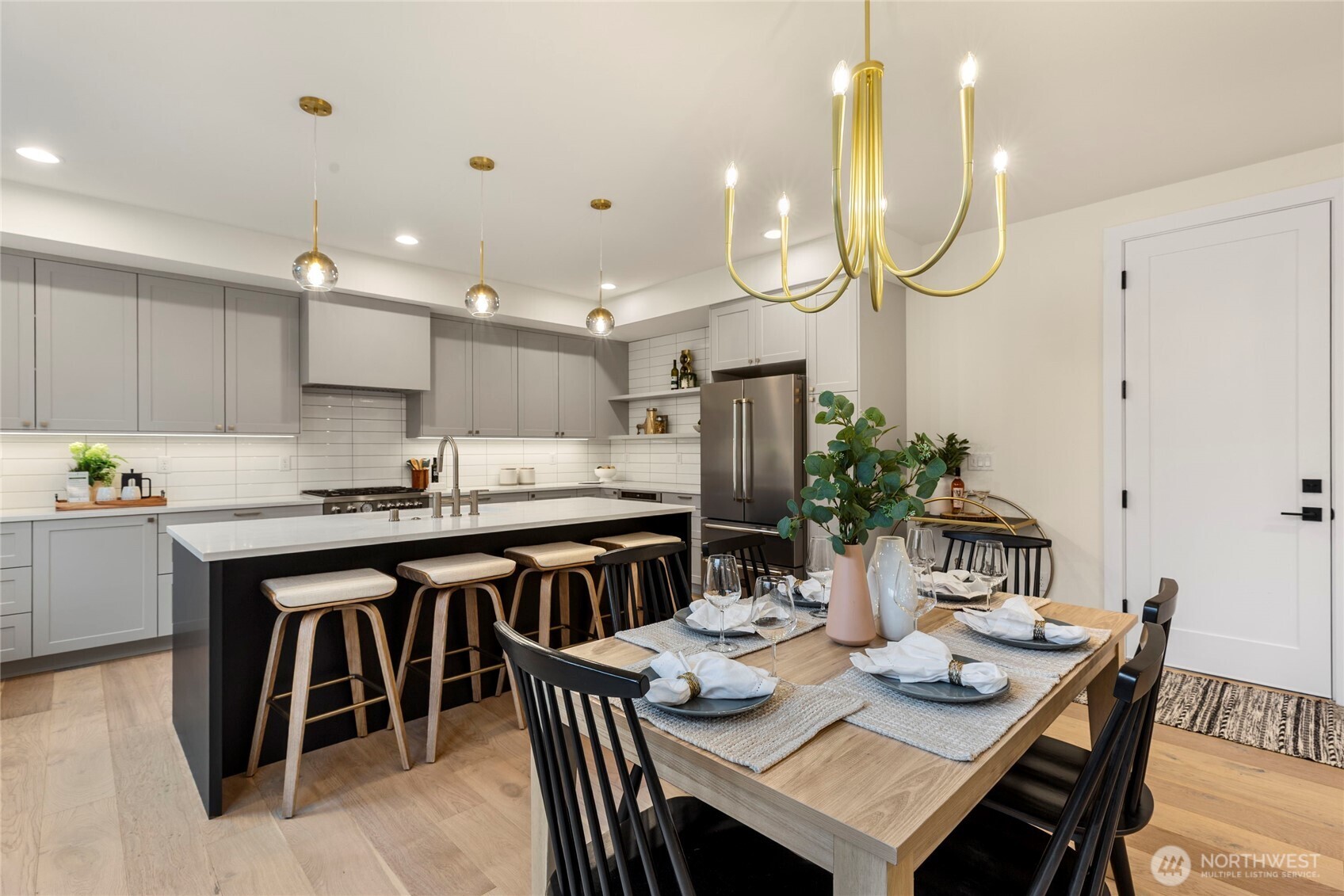 Kitchen and dining area with pendant lights, gold chandelier, recessed lighting, and natural wood flooring.