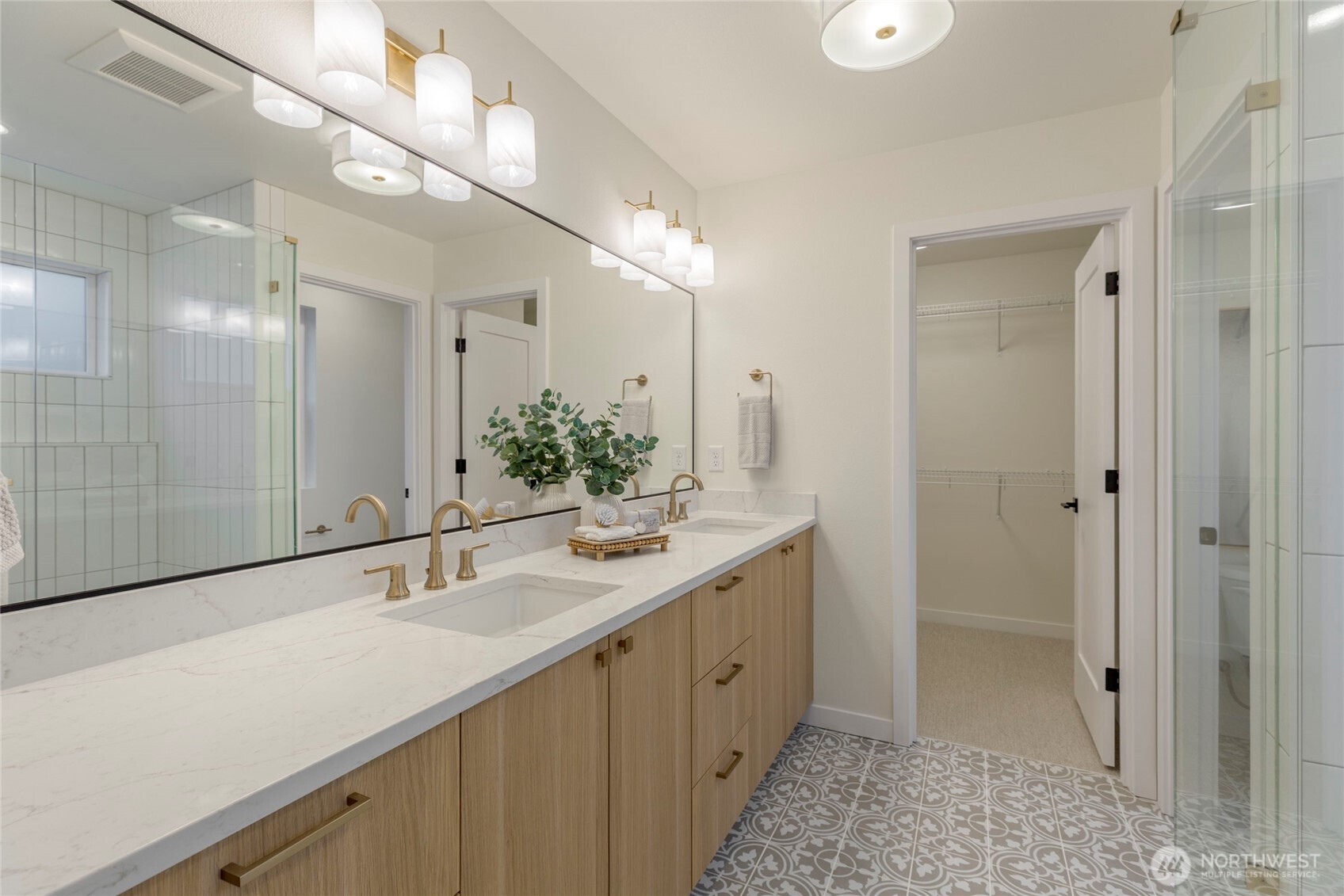 Bright bathroom with double vanity, quartz countertop, marble accents, and walk-in closet access.