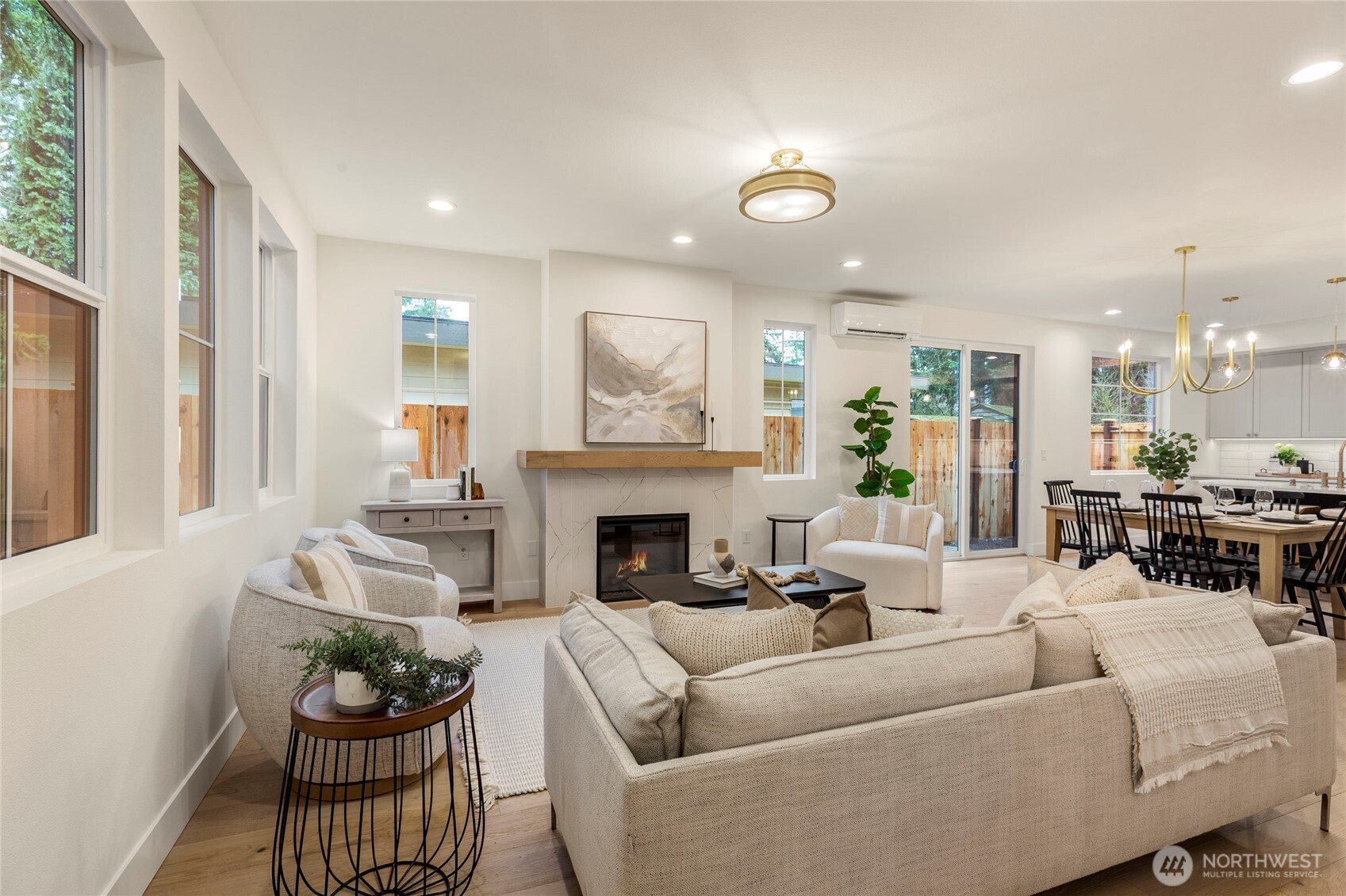 Open-concept living and dining area with recessed lighting, central ceiling fixture, large windows, and sliding glass door.