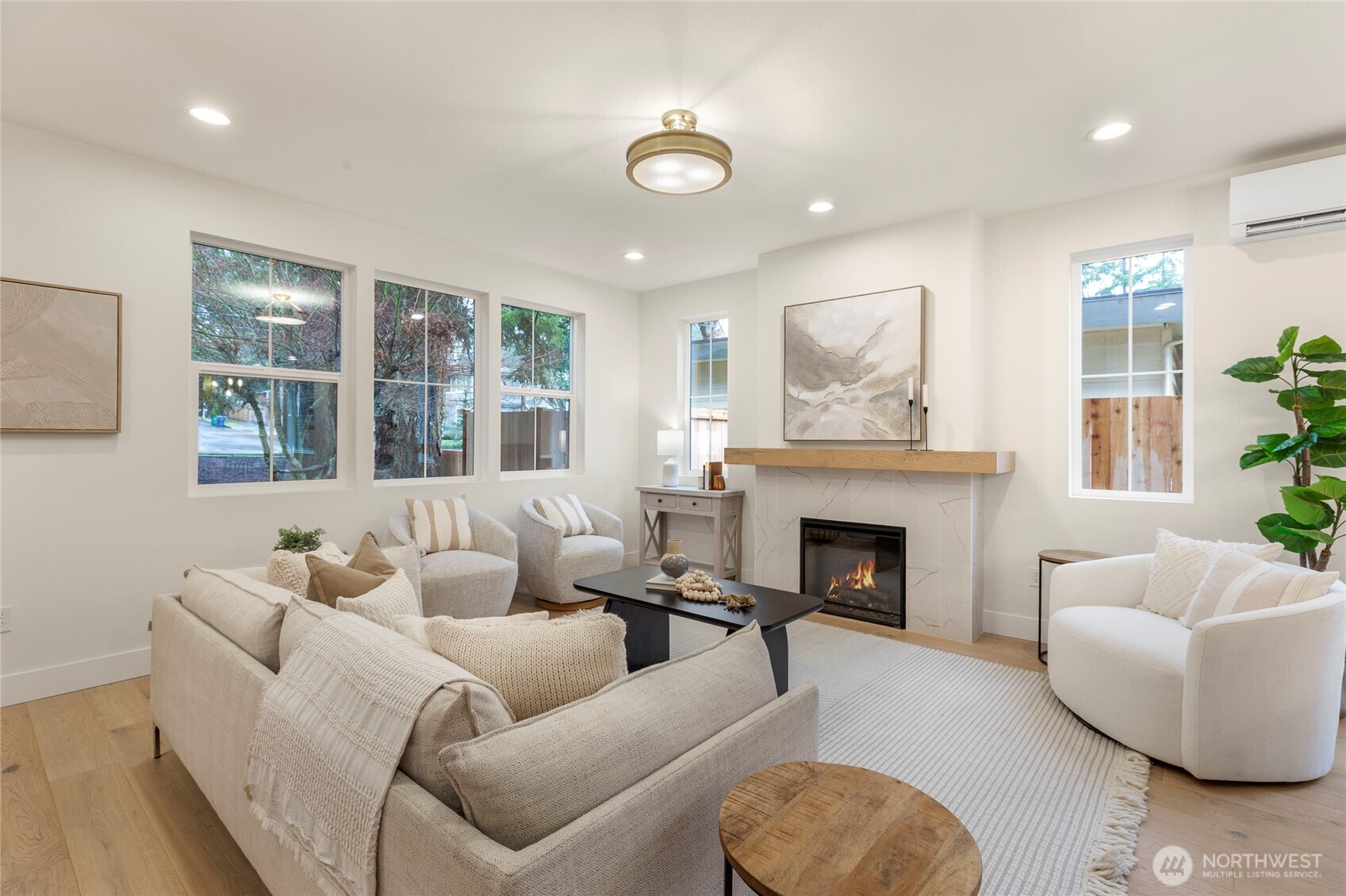 Living room with a bright fireplace, recessed lighting, and multiple windows.