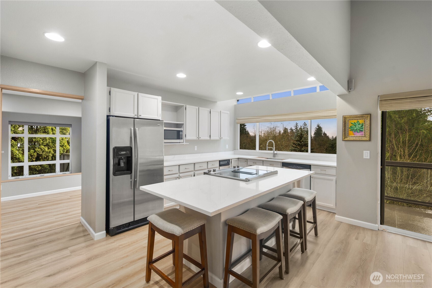Elevated modern home nestled among evergreens, offering privacy, terraced landscaping, hillside setting, and glowing interiors framed by serene natural surroundings. Easterly views of  Cascade mountains year round.
