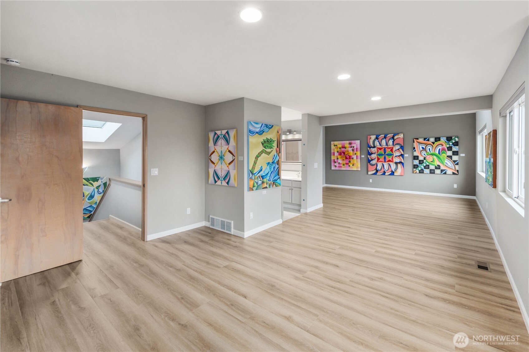 Minimalist upper walkway with warm wood accents, wide plank floors, clean lines, recessed lighting, and tranquil sightlines to nature.
