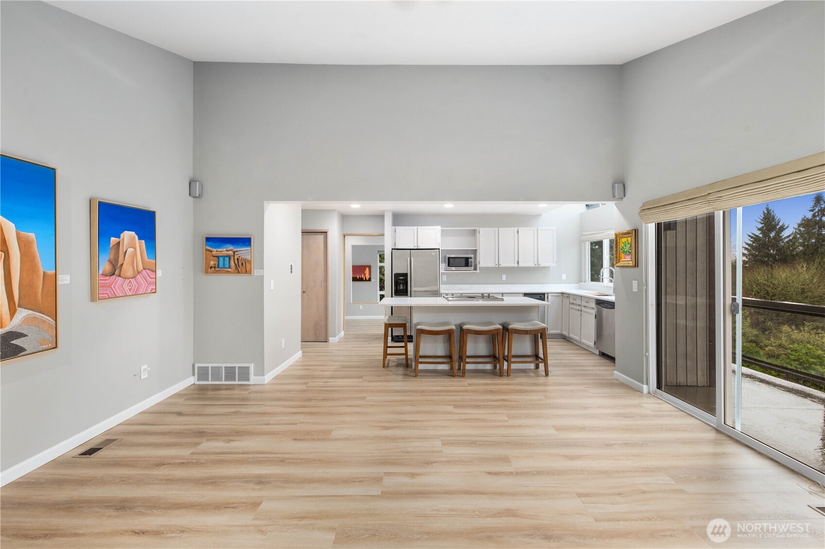 Bright modern kitchen with white cabinetry, quartz counters, skylight, stainless appliances, expansive window, and clean lines designed for effortless entertaining.