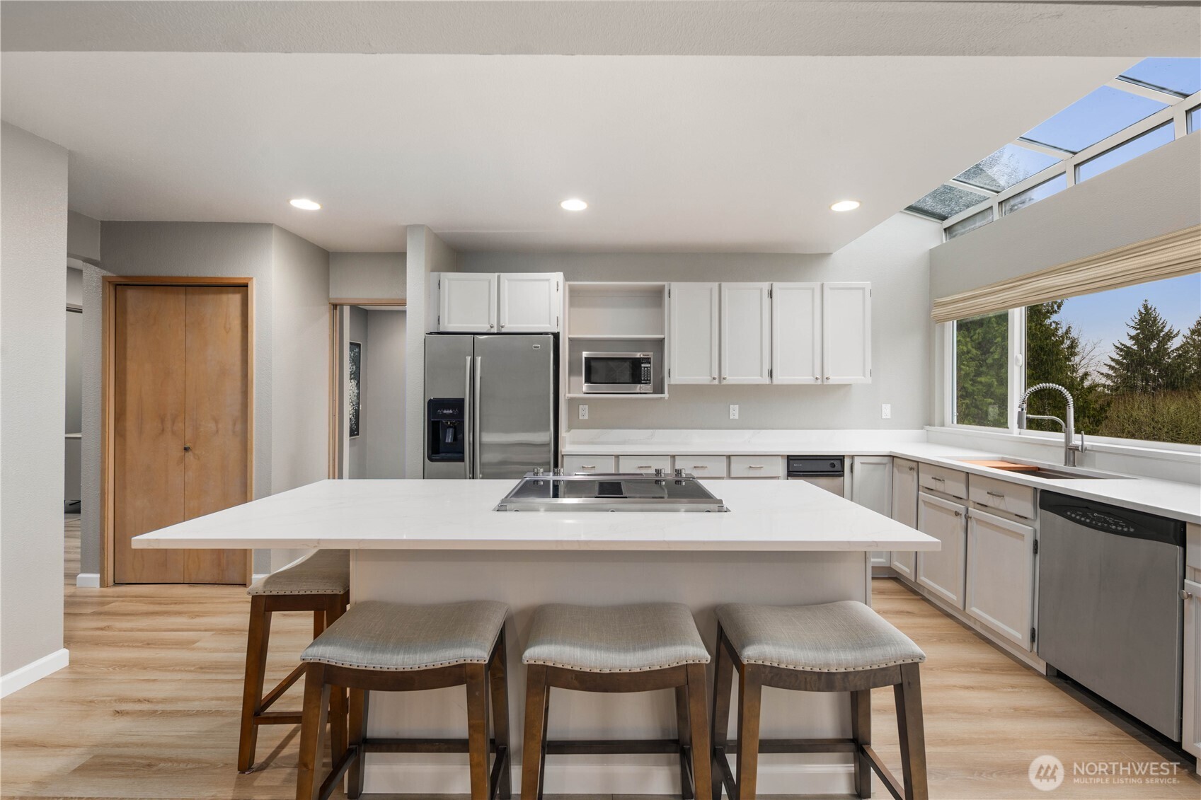 Open-concept great room featuring vaulted ceilings, wide plank floors, modern kitchen, abundant natural light, and flexible living, dining, entertaining space.